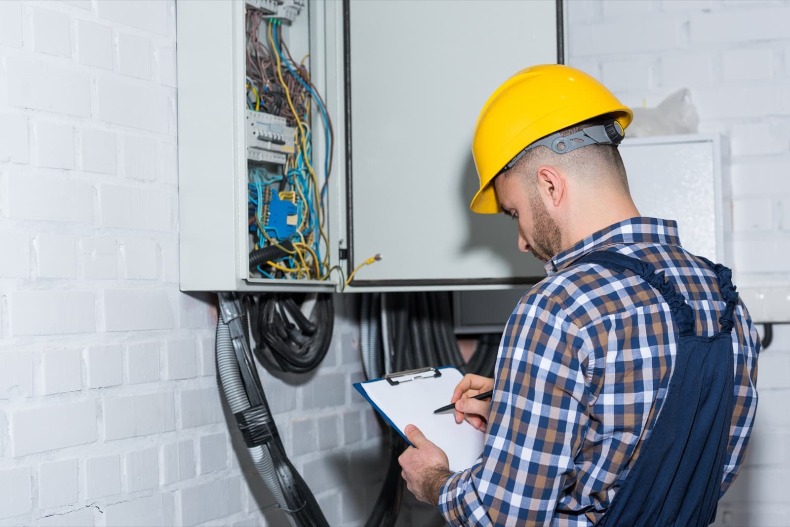 Mytek Pros electrician inspecting a low-voltage panel and wiring during an install