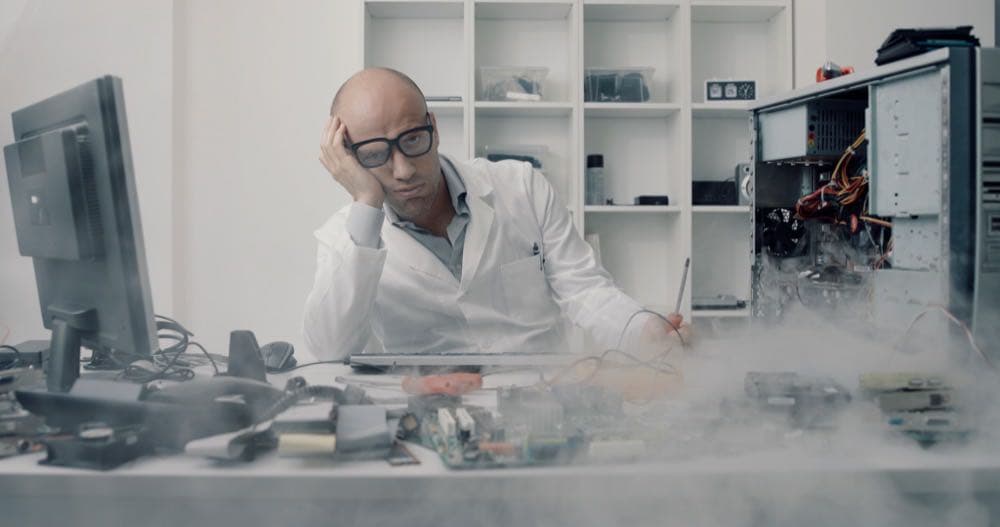 Frustrated technician looking at a broken computer representing IT problems a business shouldn't ignore