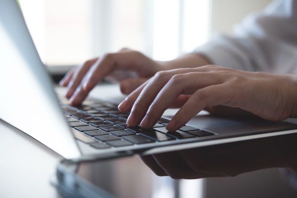 Person typing on a laptop keyboard, representing answer-engine-ready content writing