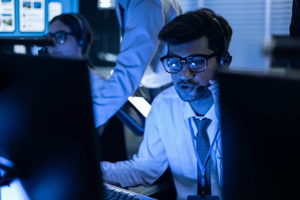 IT security analyst monitoring multiple screens in a security operations center, representing 24/7 EDR monitoring for cyber insurance readiness