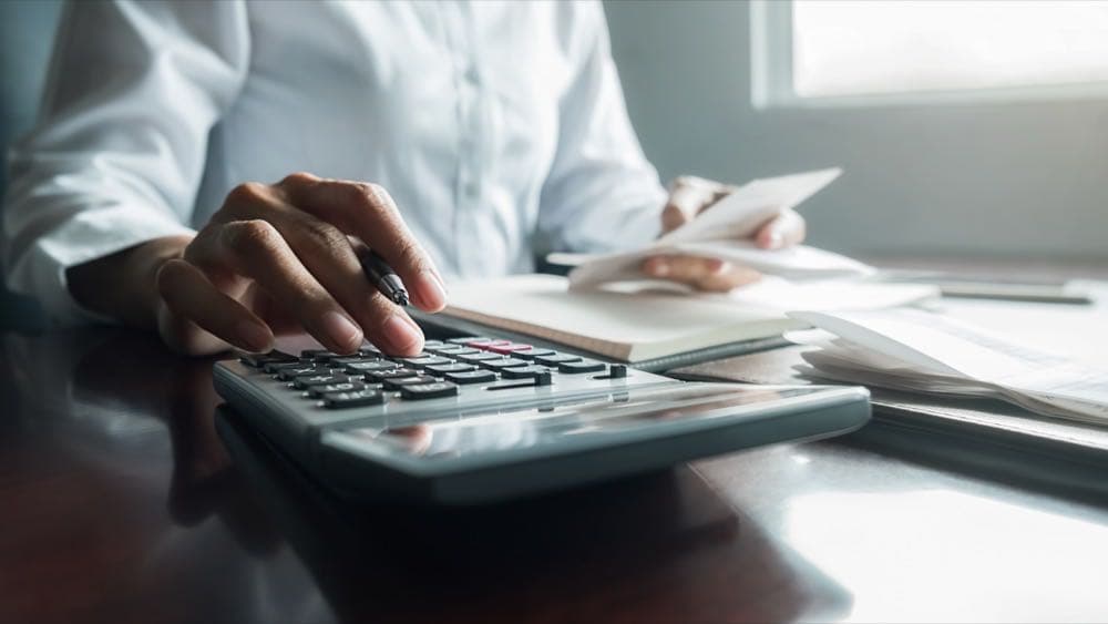 Woman reviewing bills and using a calculator representing managed IT cost planning