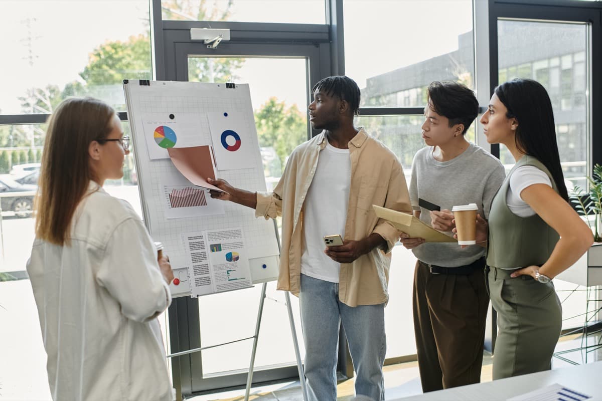 Team presenting data charts and planning a project on a whiteboard in a modern office