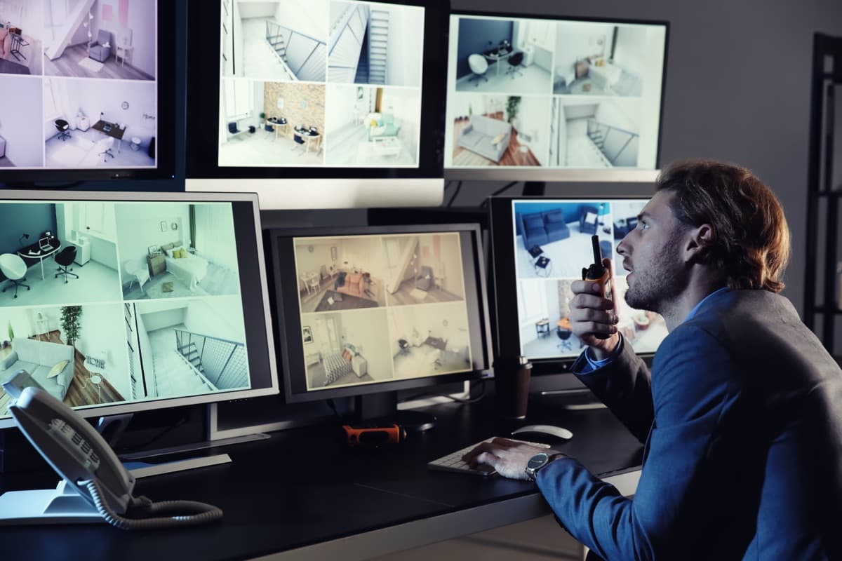 Security guard monitoring multiple CCTV surveillance camera feeds in a control room