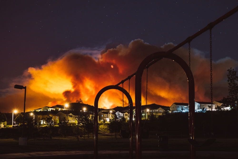 California wildfire burning at night above a residential area