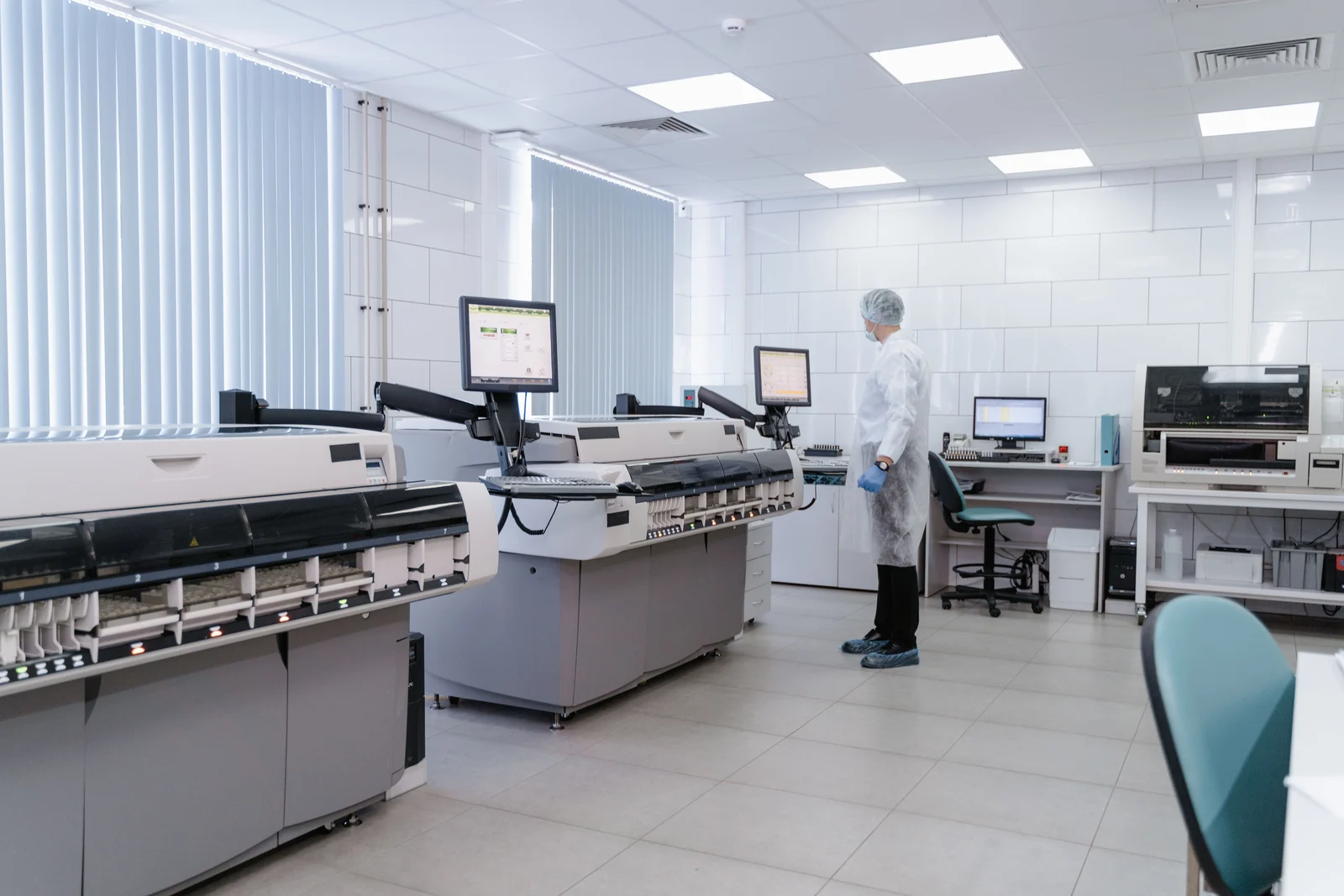 Modern laboratory with automated analyzers, connected computer monitors and a technician
