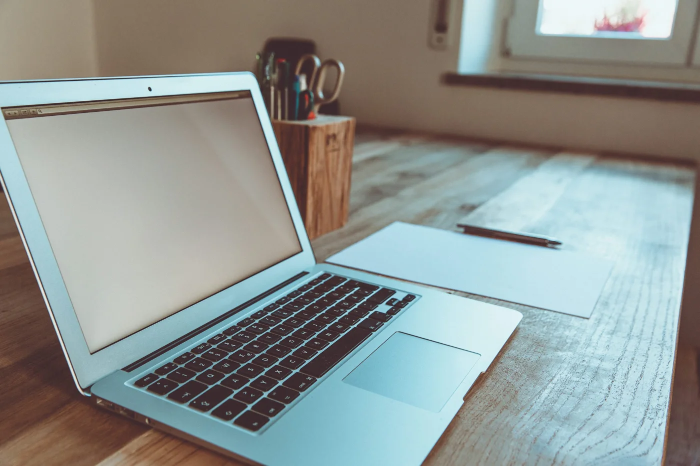 Laptop on a wooden desk in a shared workspace