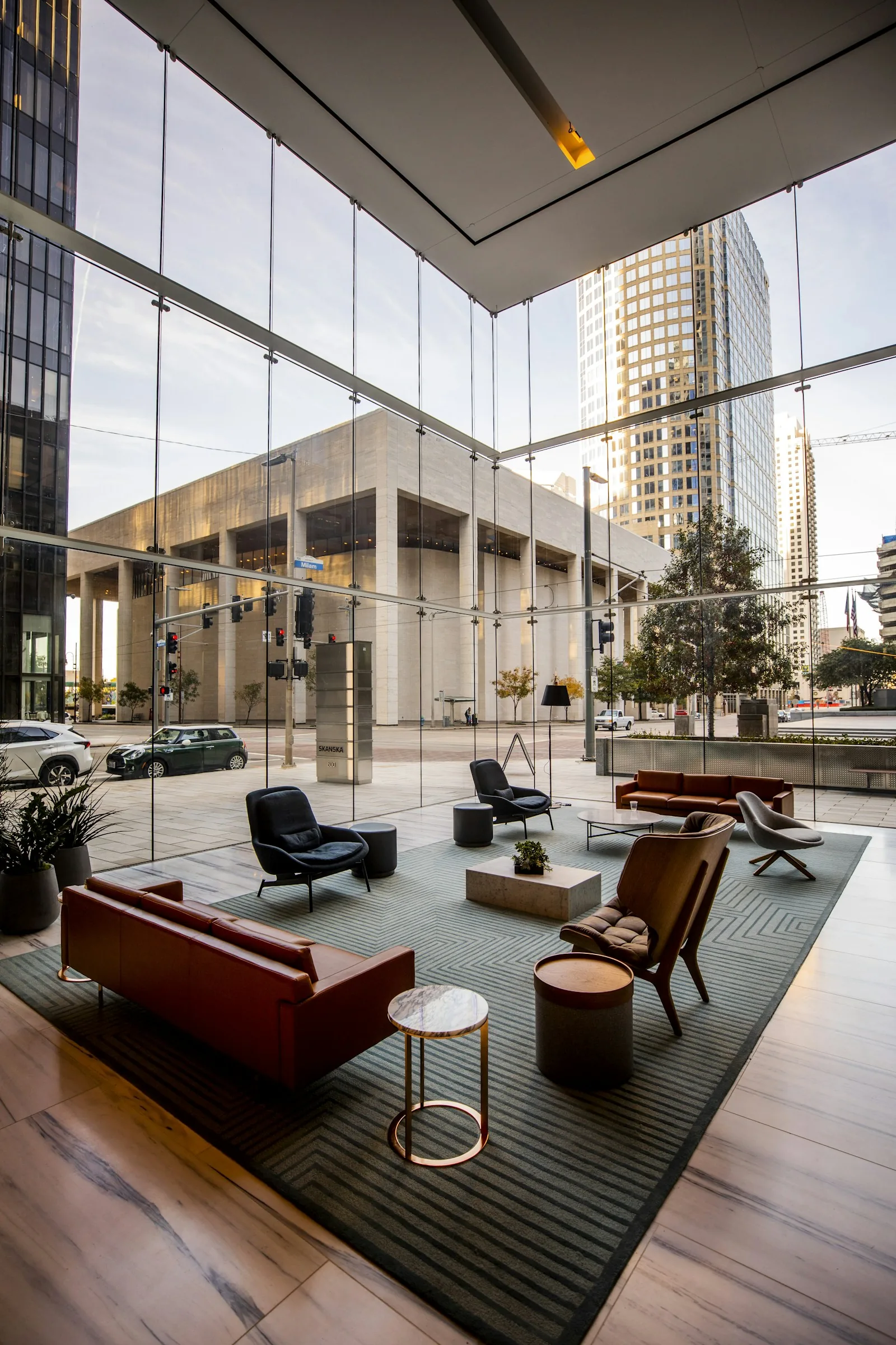 Tall glazed lobby with seating beside floor-to-ceiling windows overlooking a city street.