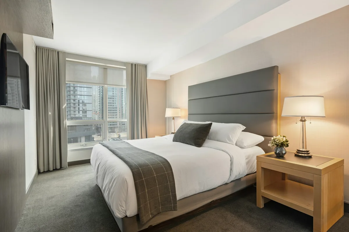 Hotel bedroom with a double bed, bedside lamps, and a window with curtains.