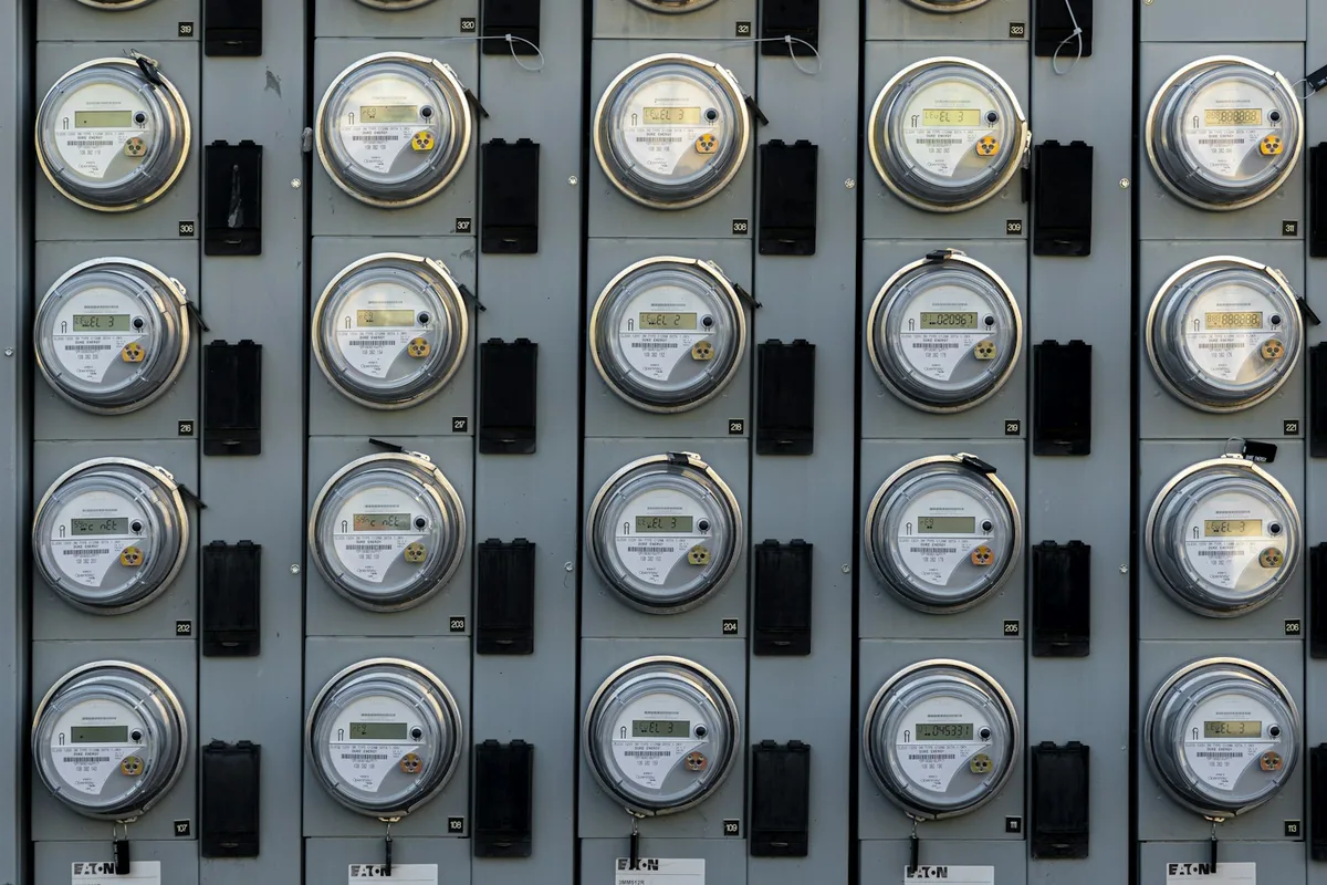 A wall-mounted bank of round electricity meters in individual metal enclosures.