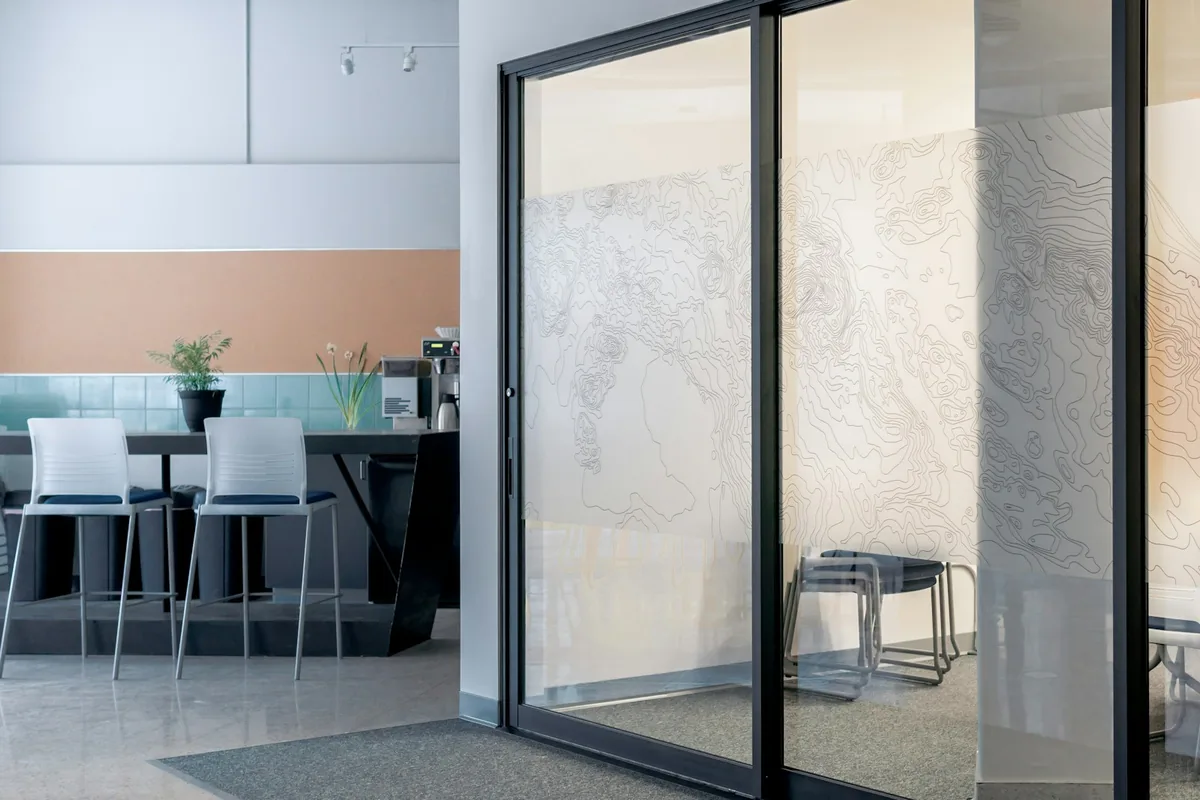 Open framed glass door beside a small furnished meeting area.