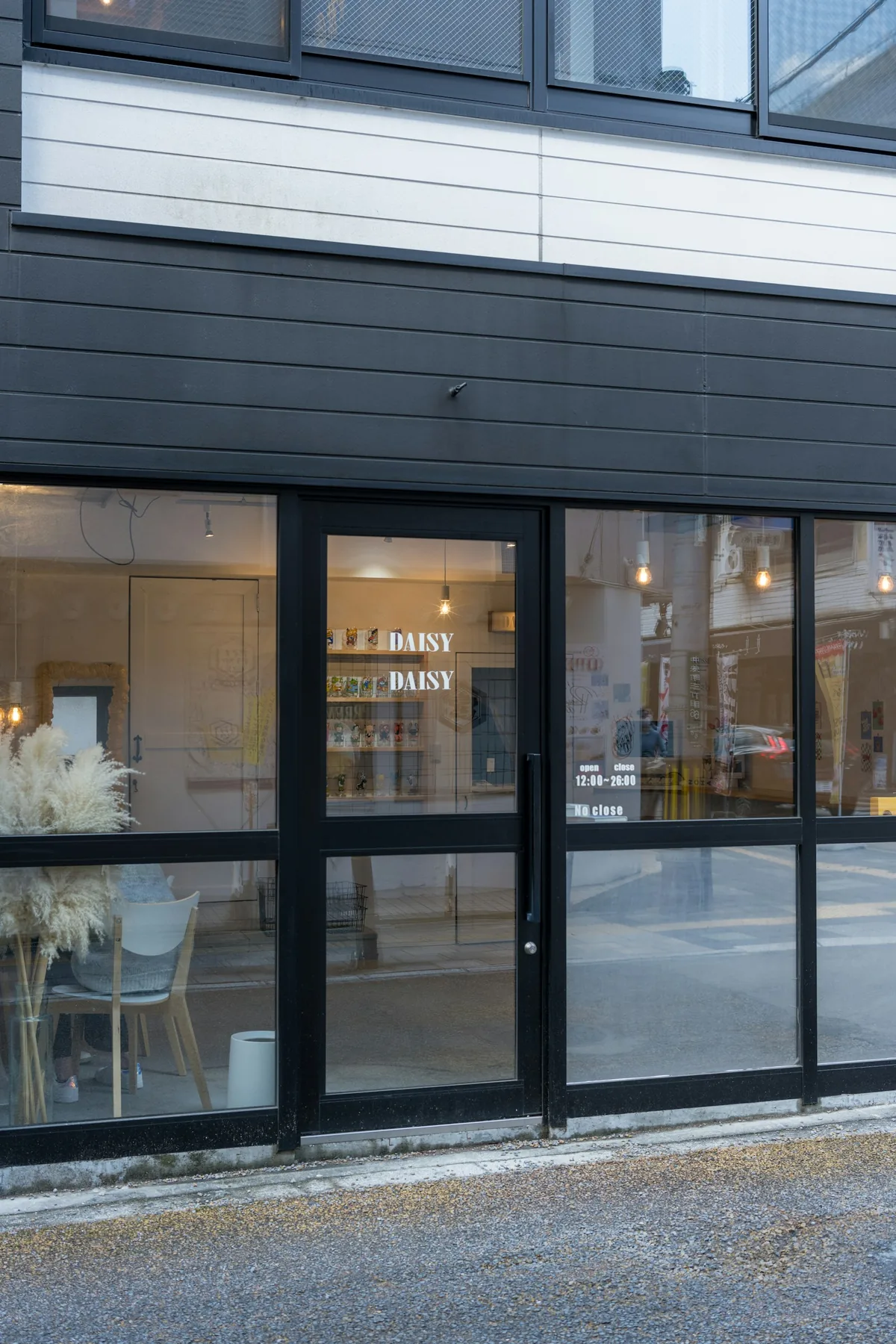 Closed black-framed glass shop doors and display windows beside a pavement.