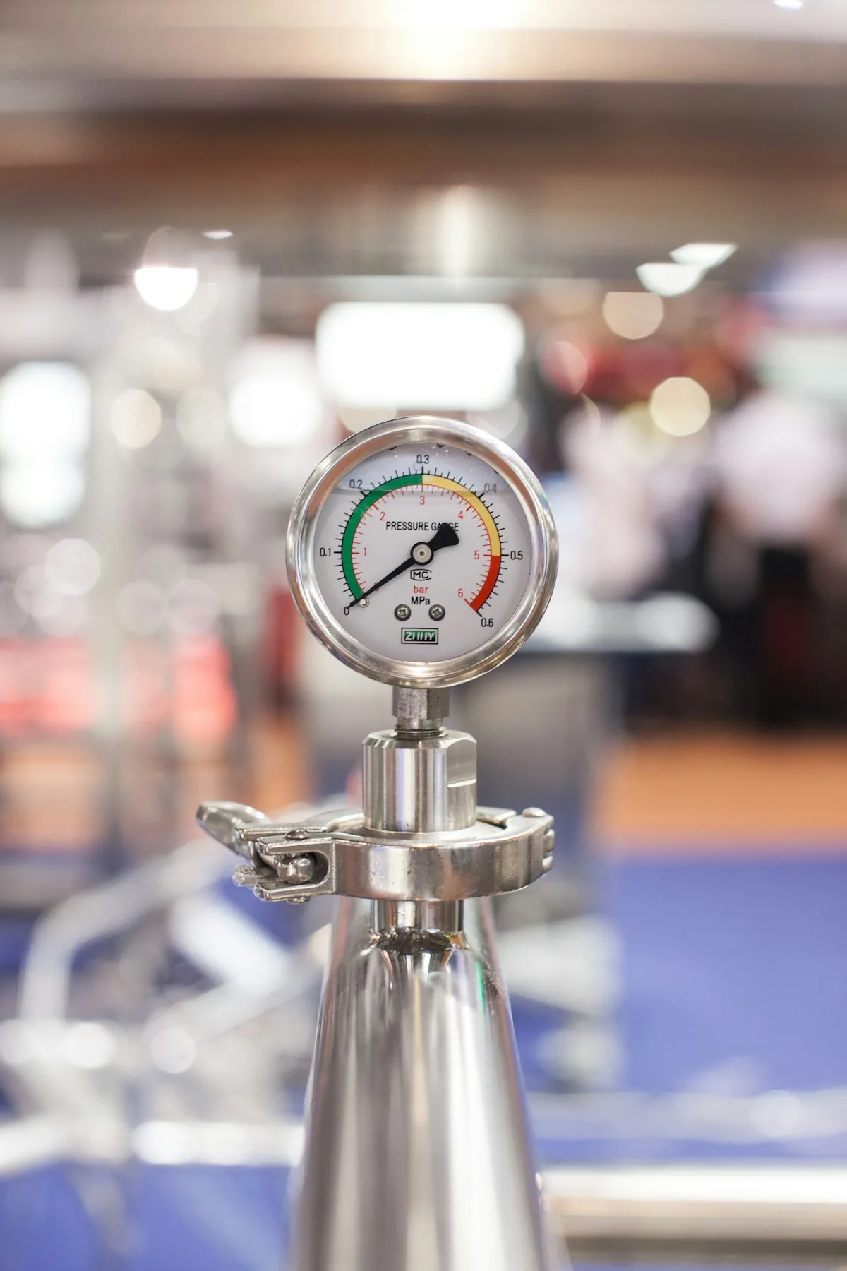 Round analog pressure gauge mounted on a stainless-steel pipe fitting.