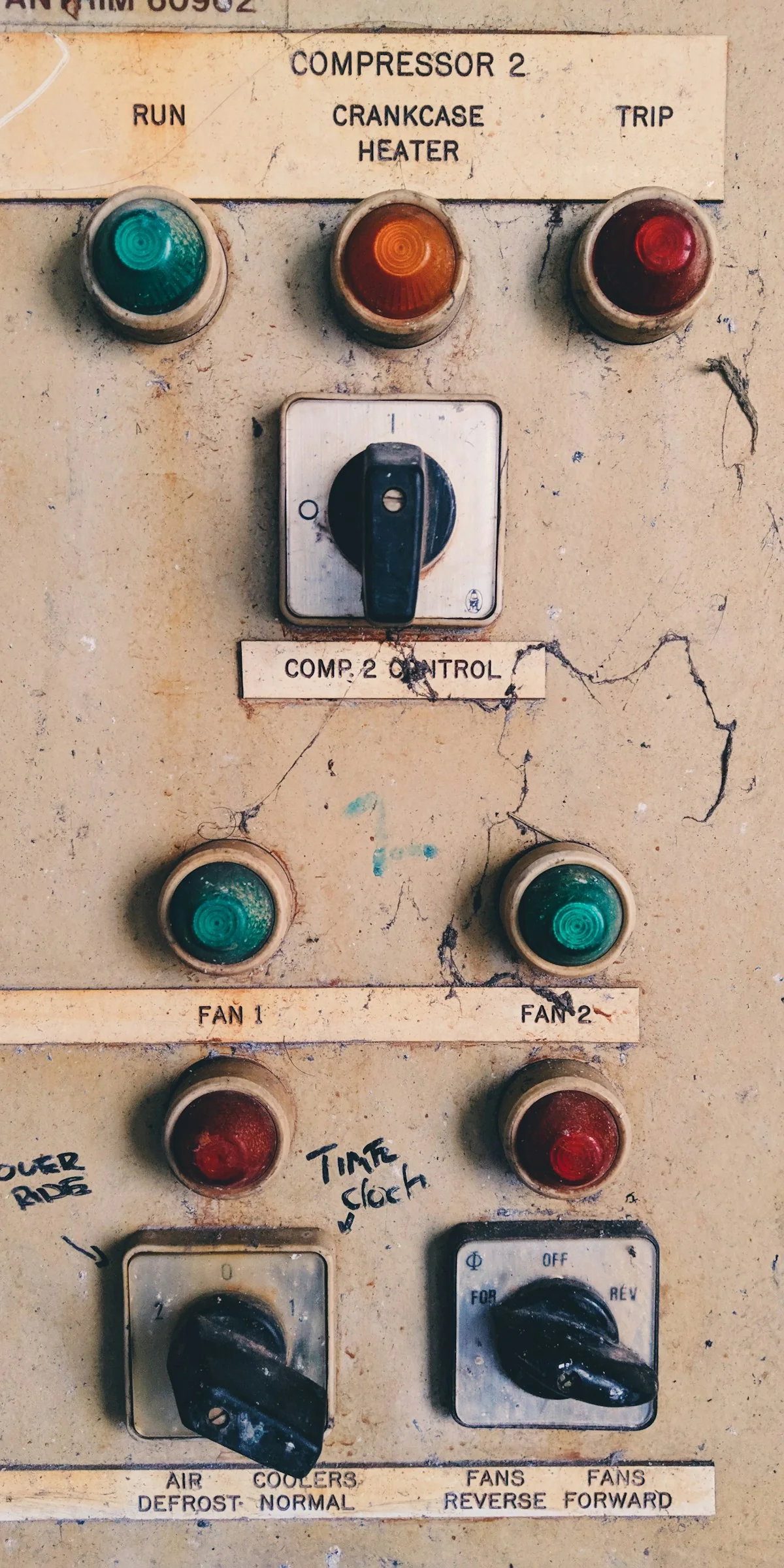 Indicator lamps and selector switches on a weathered compressor-and-fan control panel.