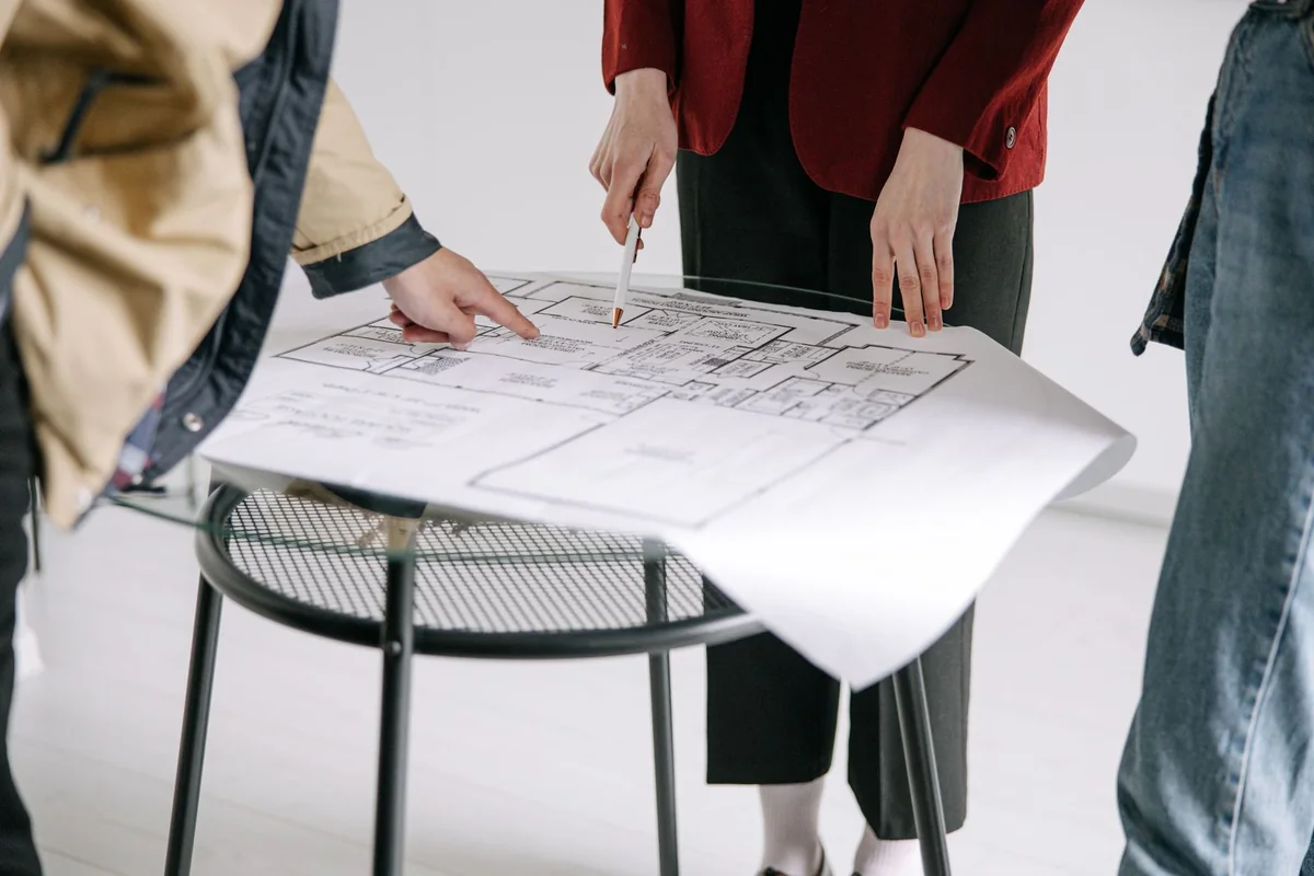 People reviewing a printed building floor plan together at a round table.