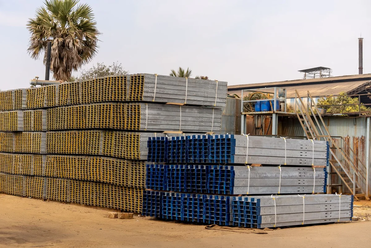 Stacks of metal sections and materials arranged in an outdoor industrial yard.