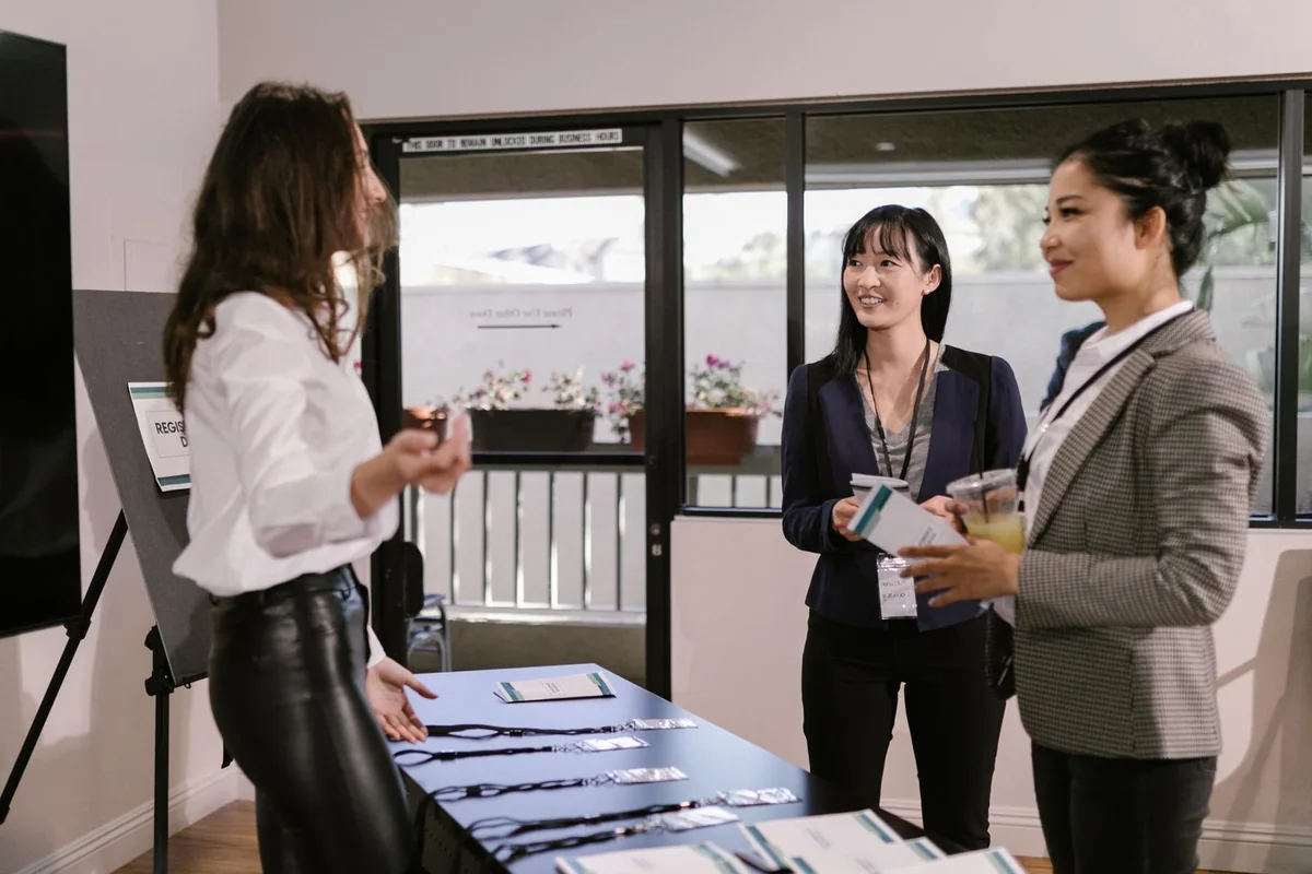 Attendees speaking with a staff member at a conference registration table.