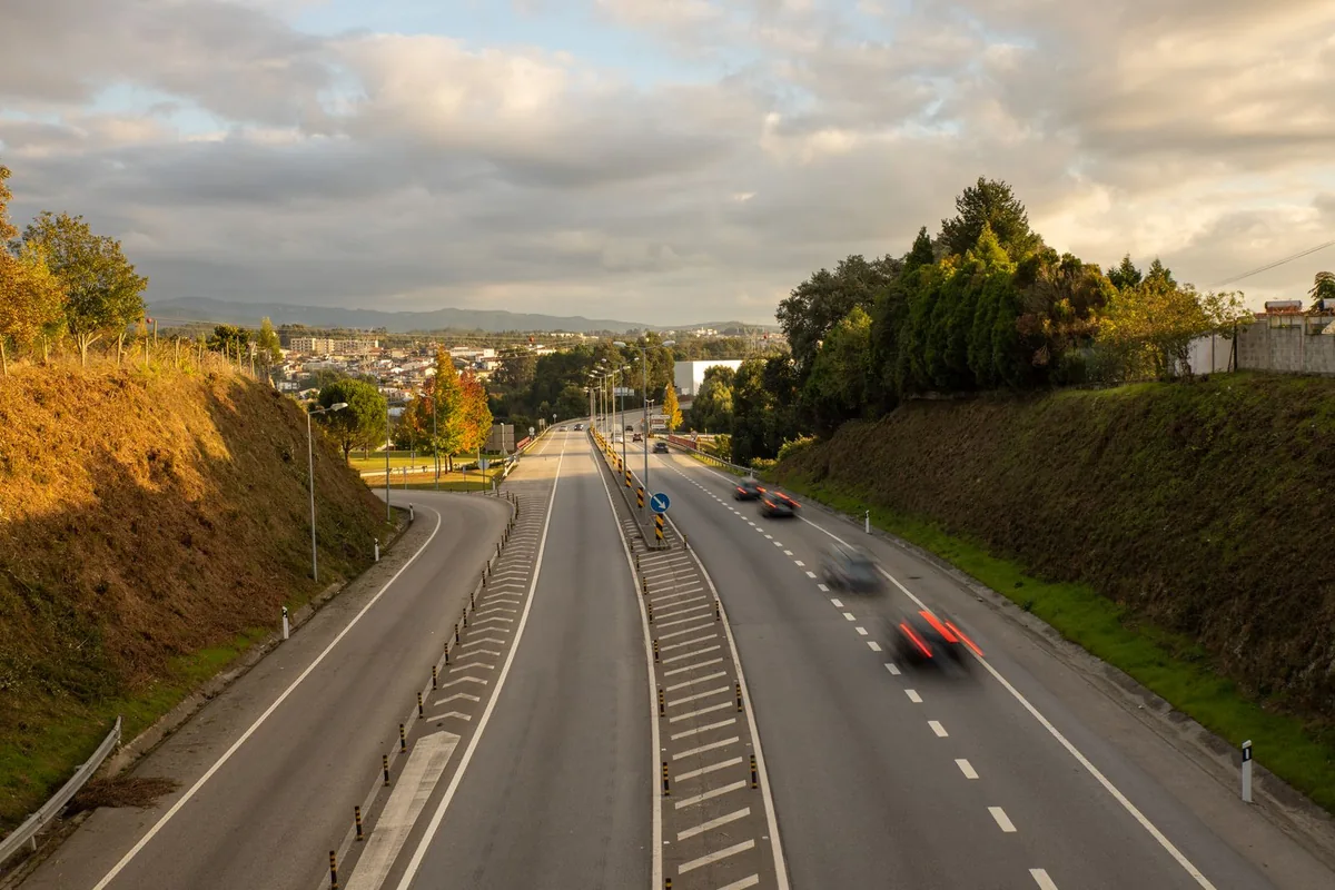 Cars travelling along a divided road viewed from above in evening light.