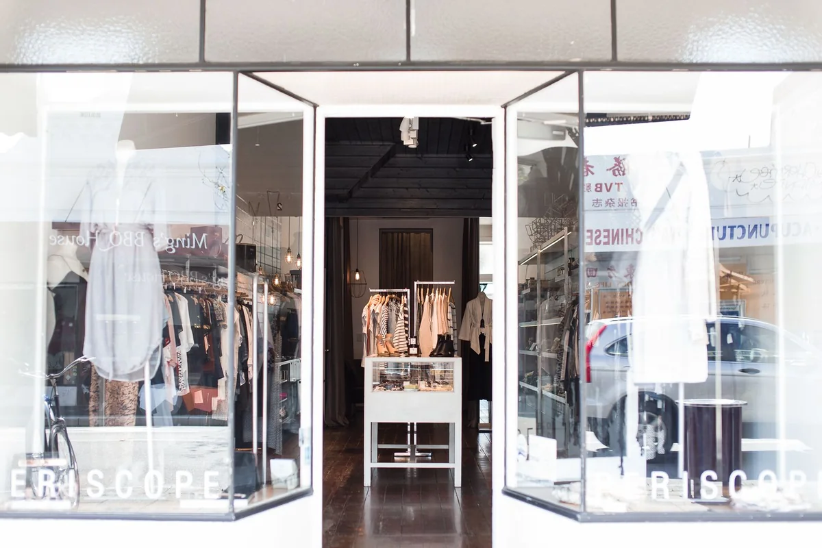 Open glass doors between the display windows of a clothing boutique.
