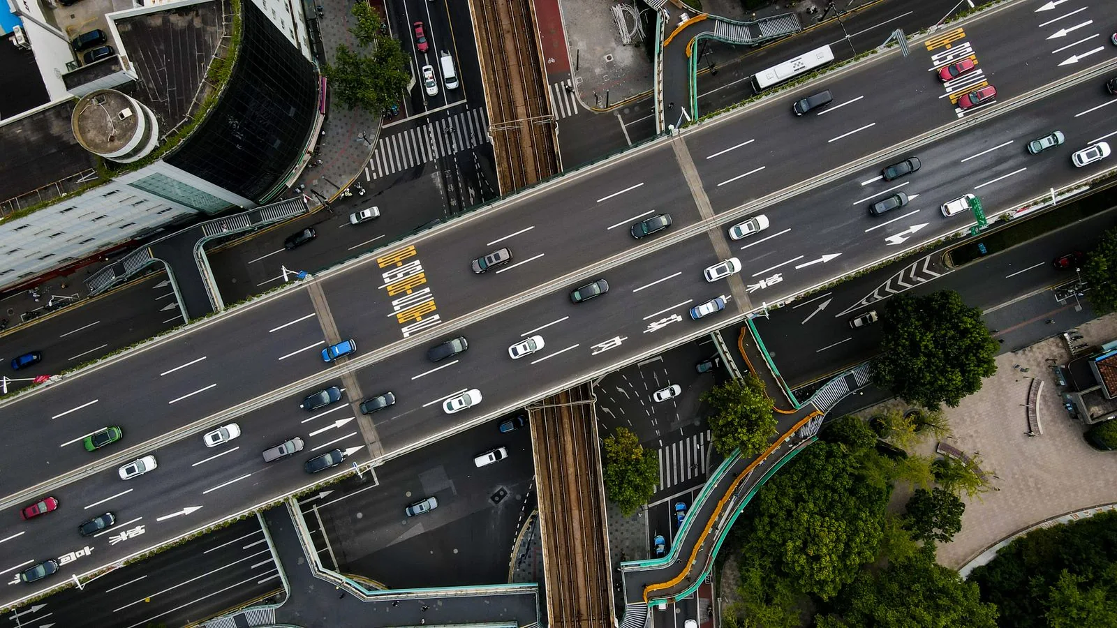 Overhead view of cars and buses on a multilane urban road and adjoining approaches.