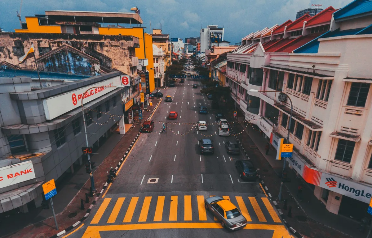 Elevated view along a city road with vehicles and a yellow-striped pedestrian crossing.