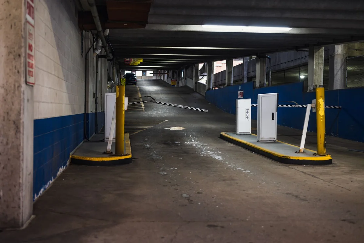 Two access lanes with barrier arms and control posts at an underground car park.