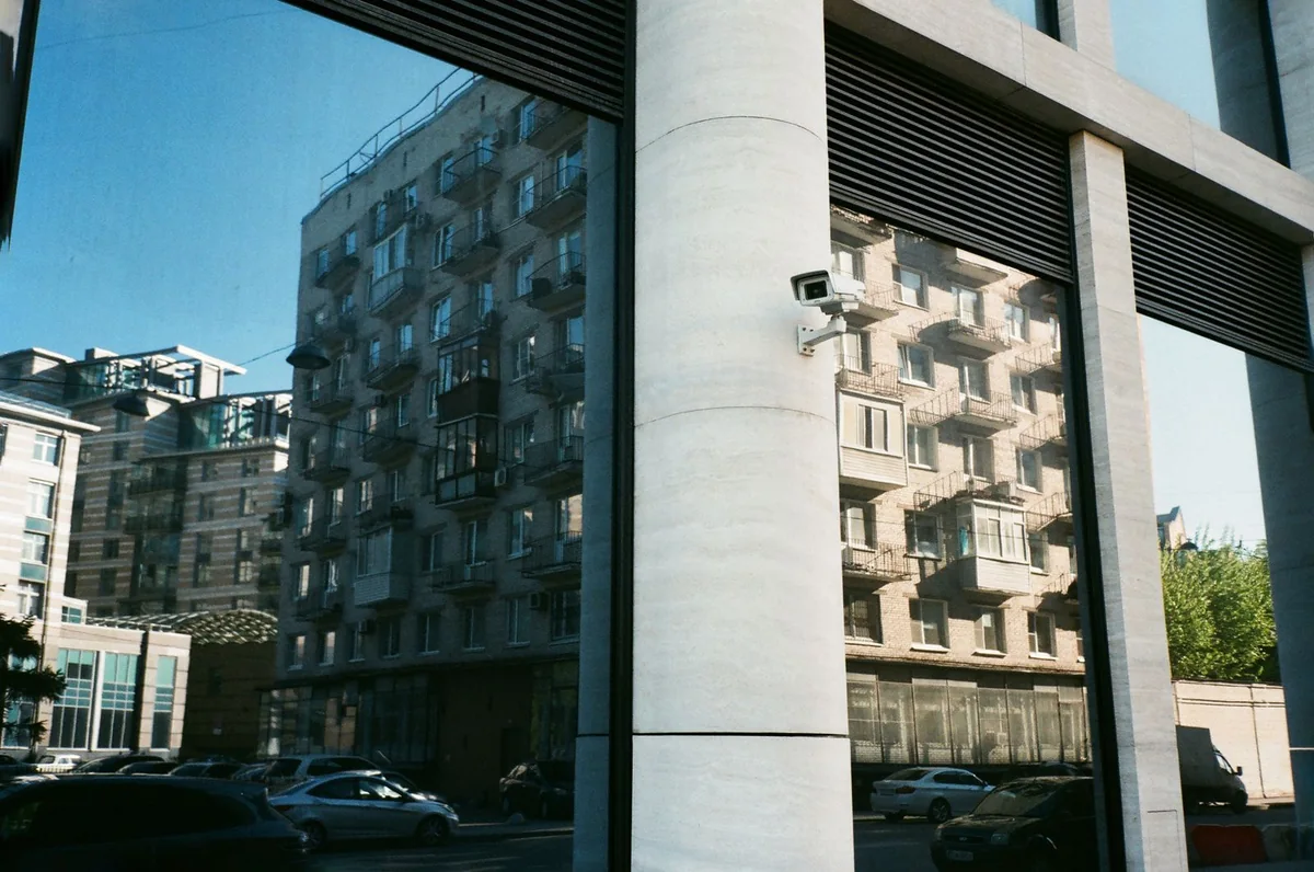 Small security camera mounted beside reflective windows on a commercial building.