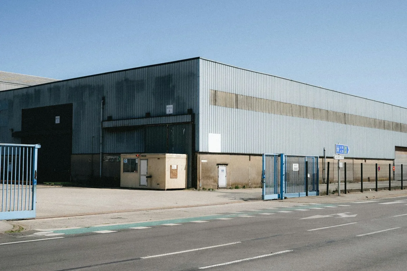Blue access gates outside an industrial warehouse.