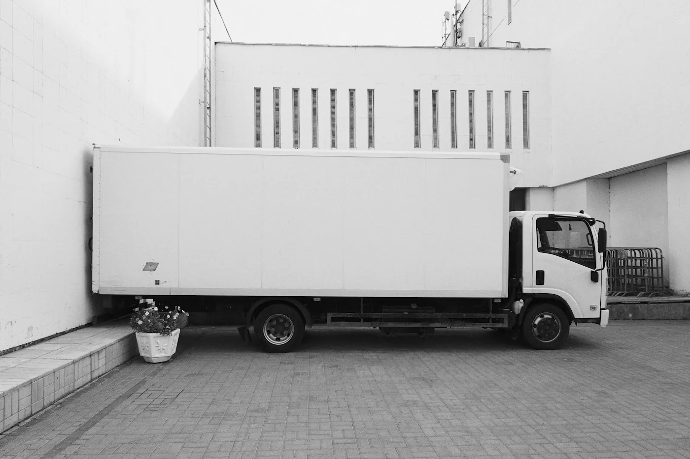 White box truck parked at a commercial loading entrance.