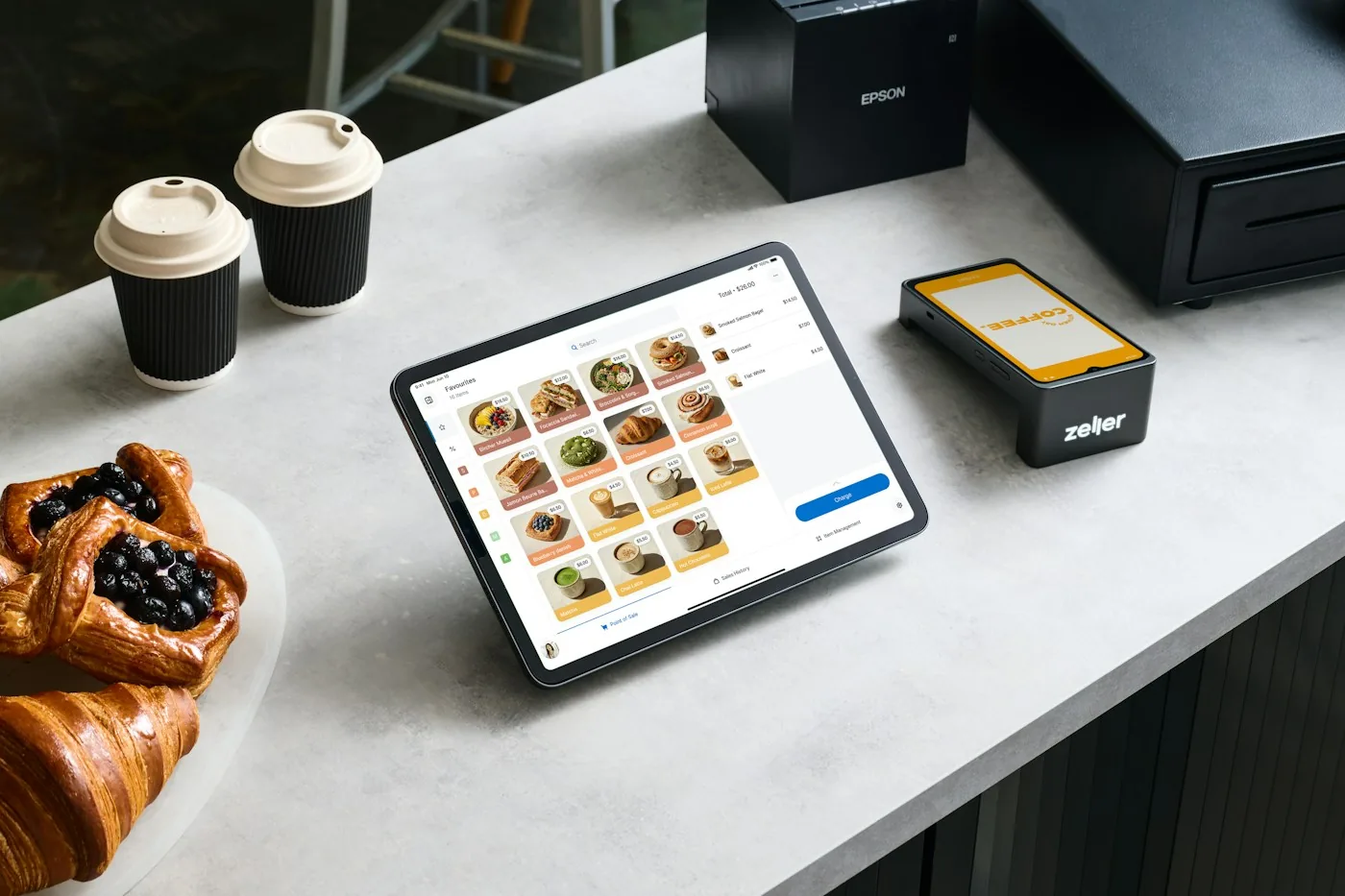 Tablet point-of-sale system, payment terminal and receipt printer on a cafe counter.