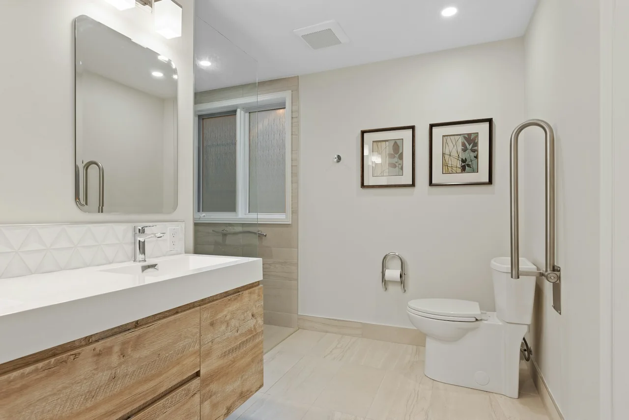 An accessible bathroom with a wide entrance, basin and grab rails beside the toilet.