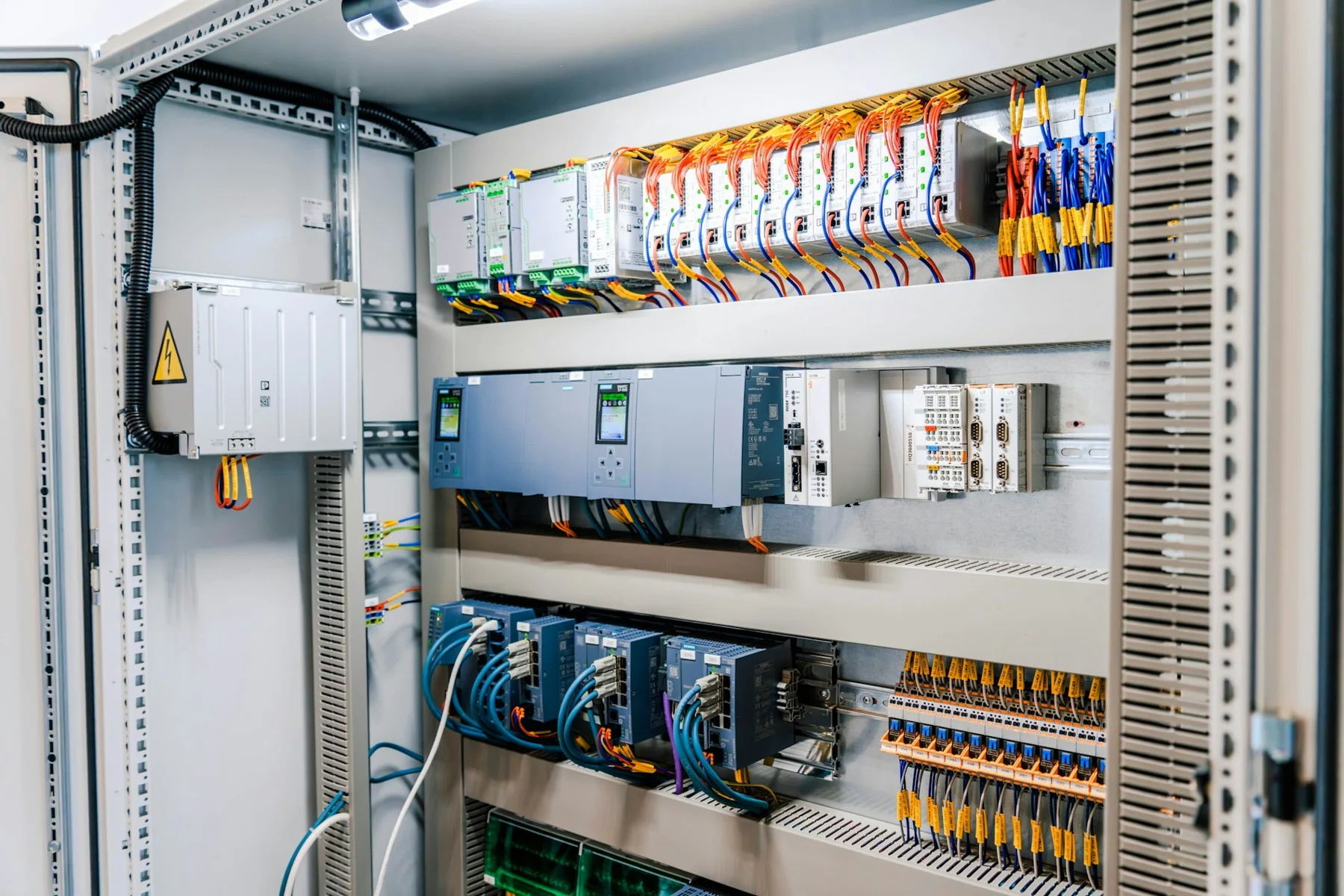 Open industrial electrical control cabinet with terminal blocks, wiring and control modules.
