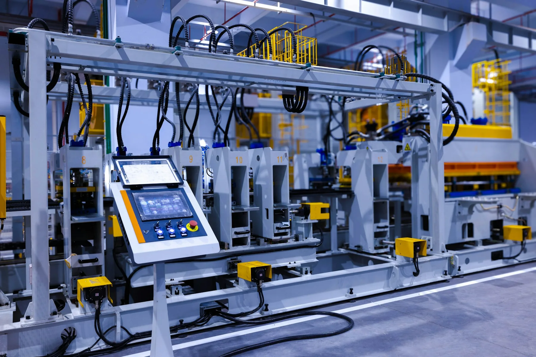 Industrial production machine with a local operator control screen and guarded work area.