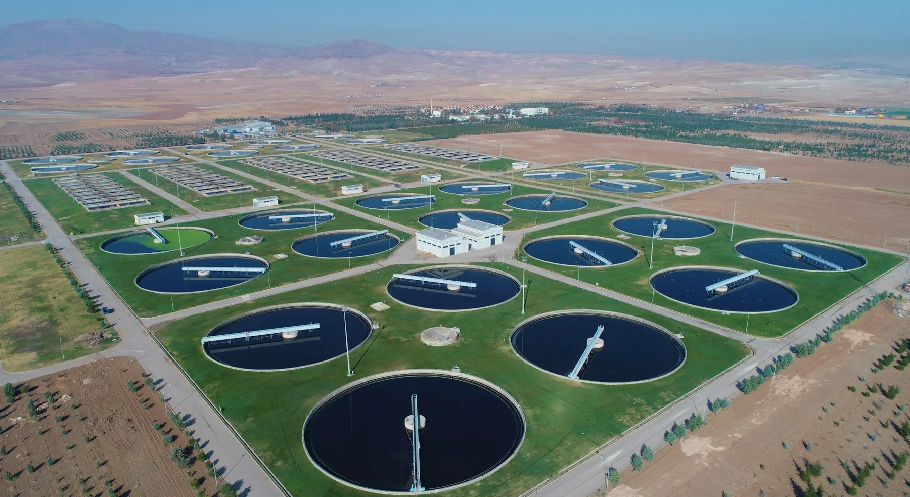 Water-treatment facility with circular basins in an open landscape.