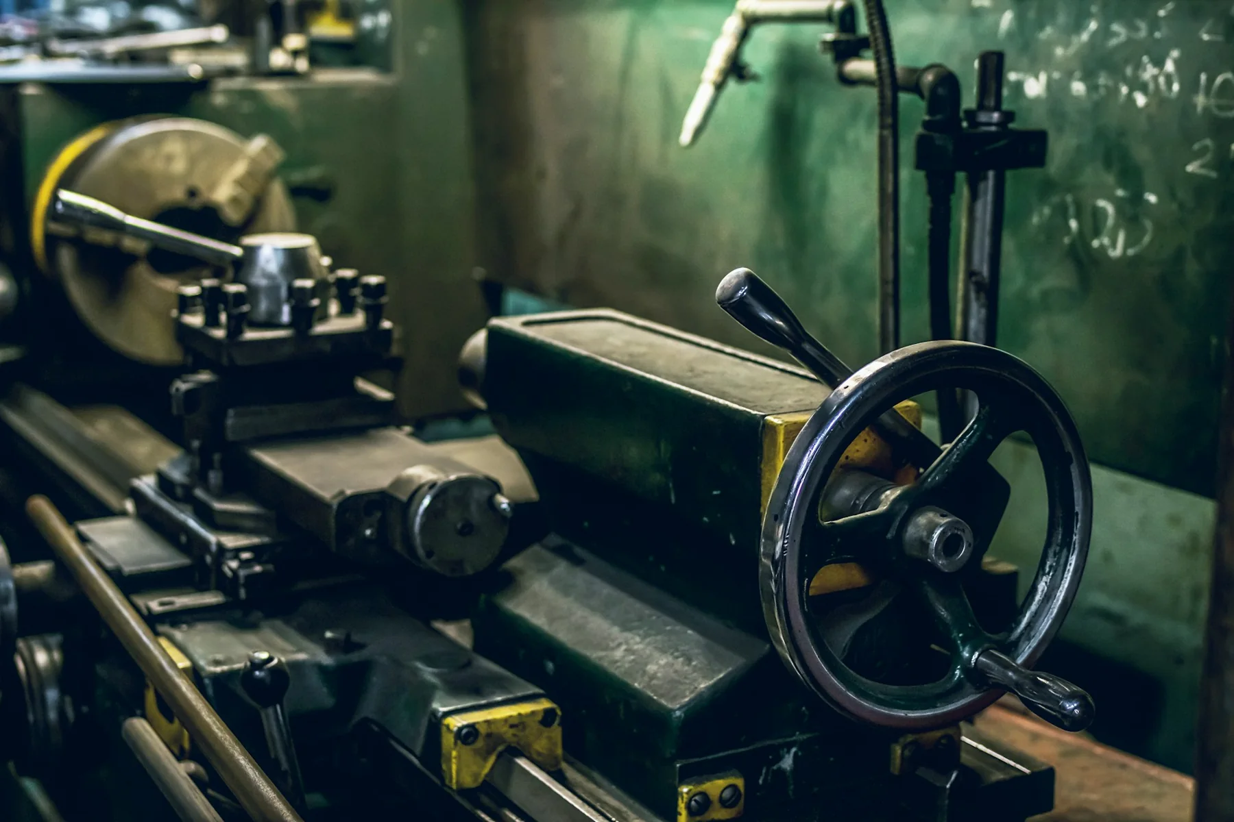 Metalworking lathe with a handwheel and tool carriage inside a workshop.