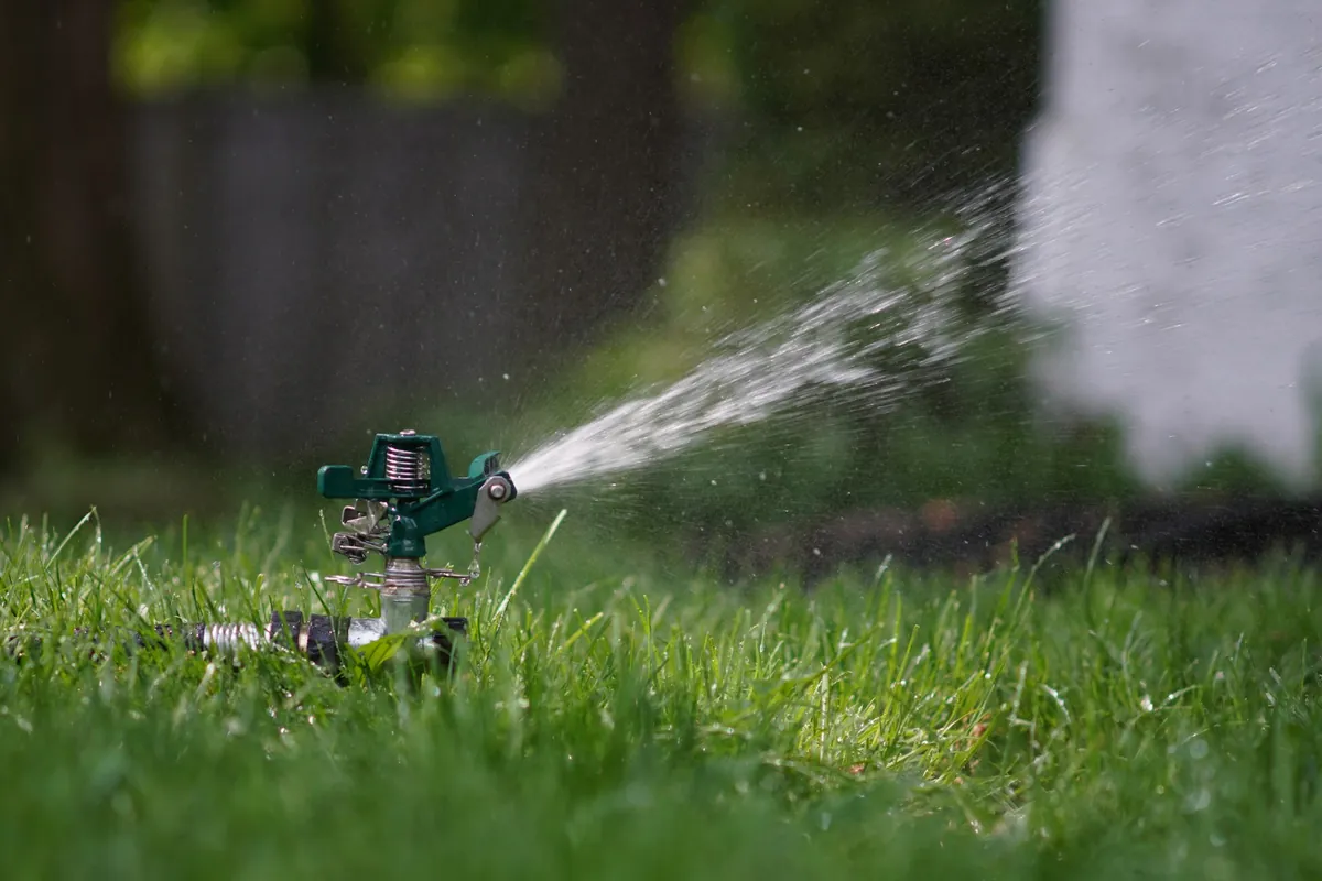 A lawn sprinkler spraying water across green grass.