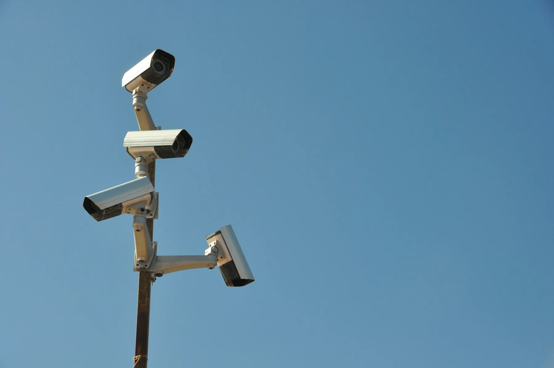 Four exterior surveillance cameras facing different directions from one pole.