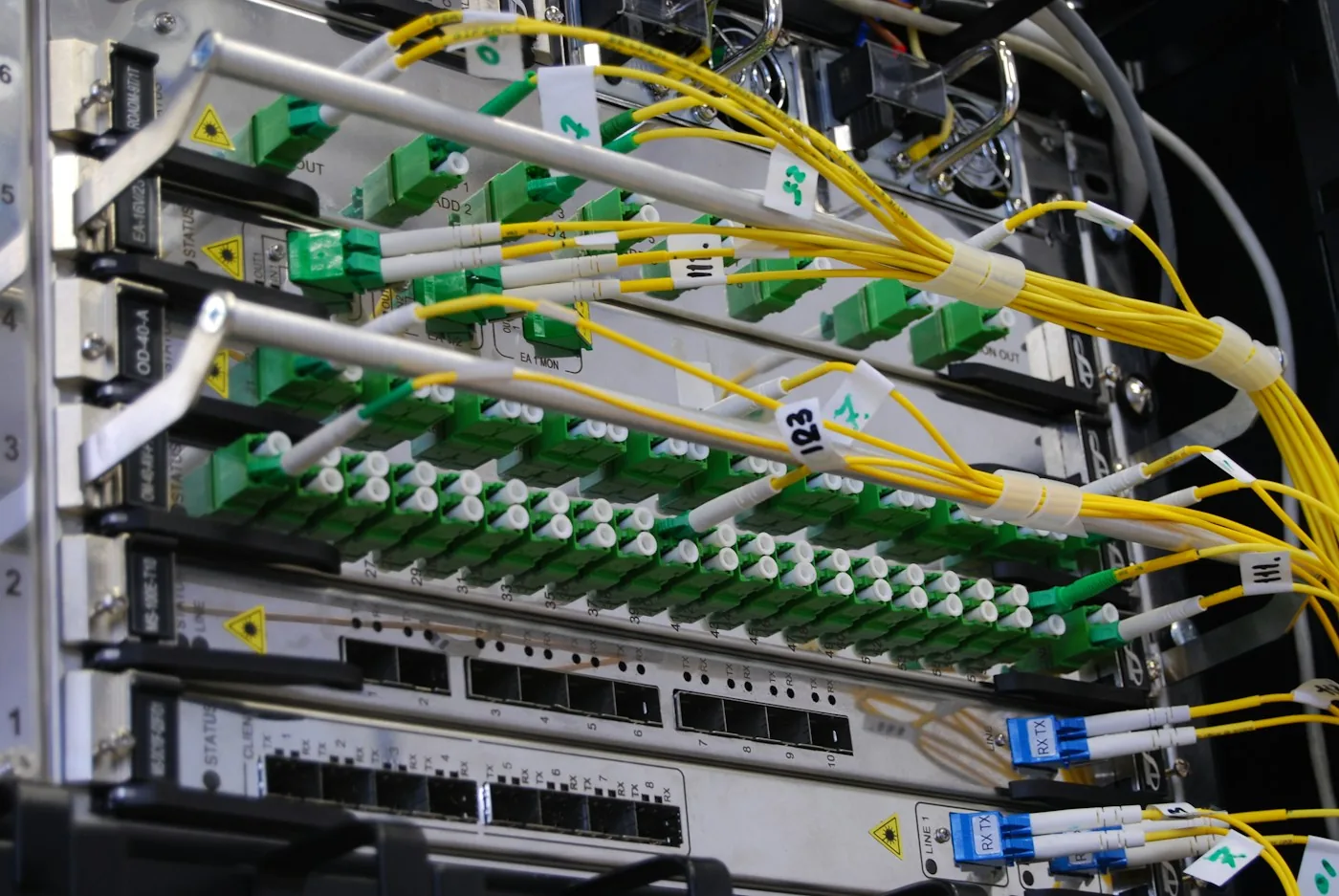 Labeled fiber-optic leads connect equipment in a network rack.