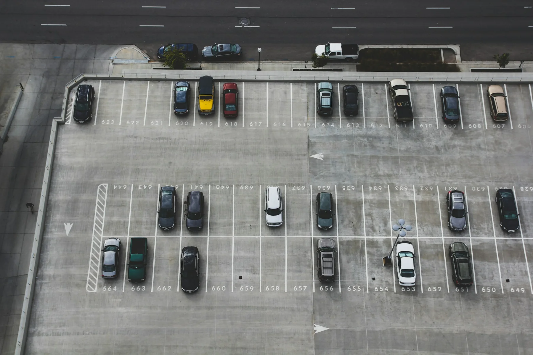 Overhead view of marked parking bays with both parked cars and empty spaces.