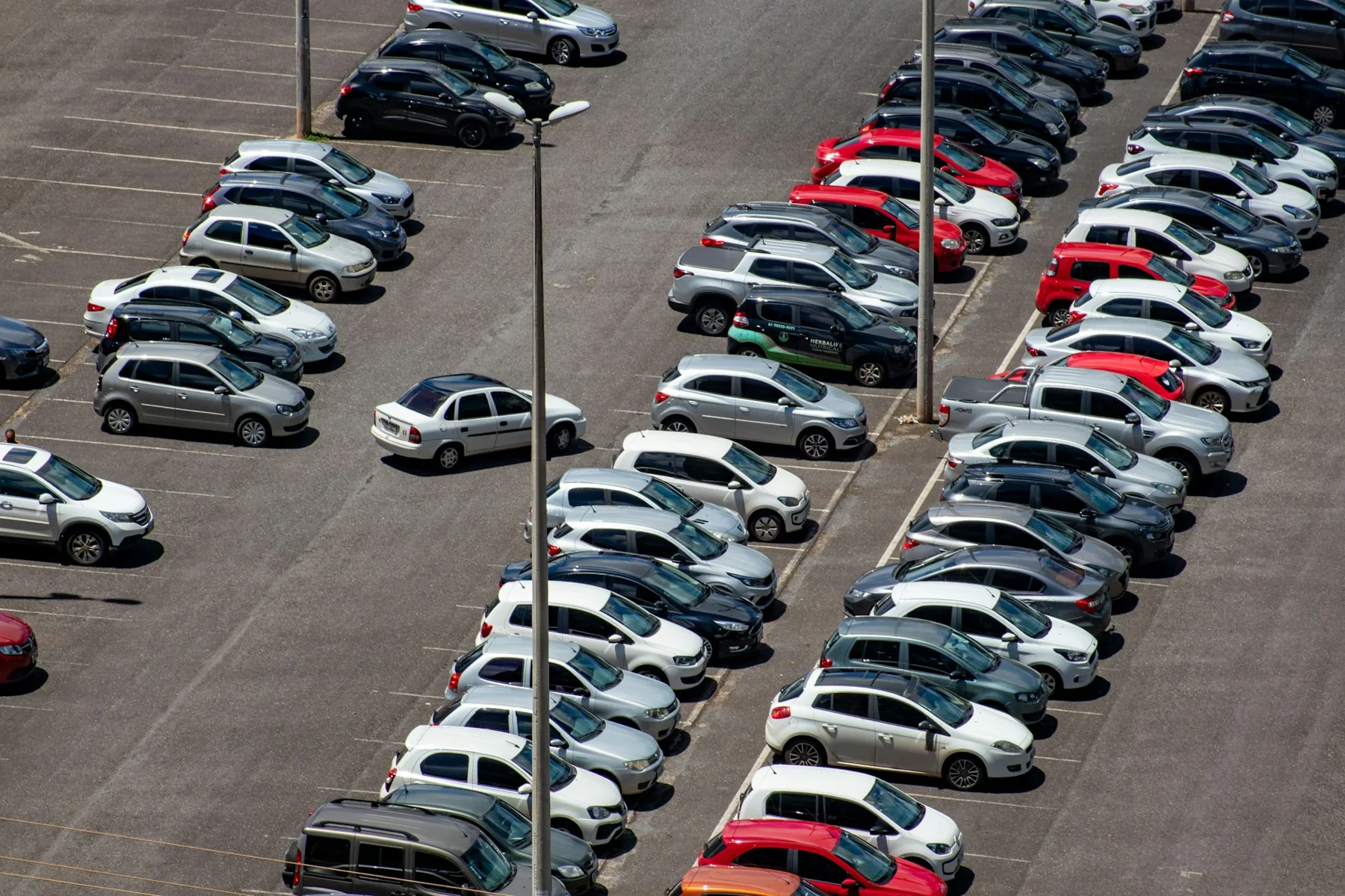 Rows of parked cars and open bays viewed diagonally from above.