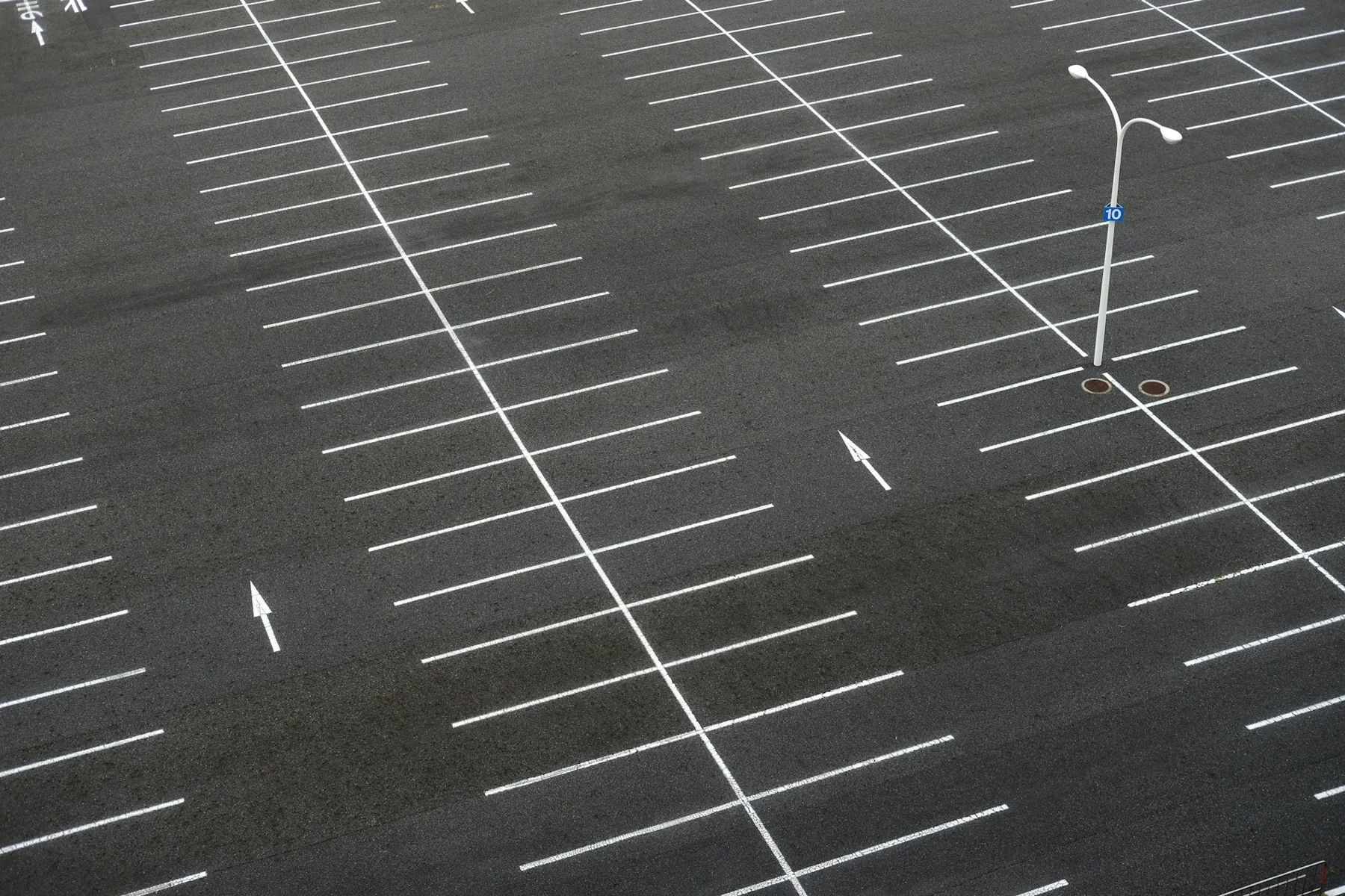 Wide empty outdoor parking lot with white bay markings and light poles.
