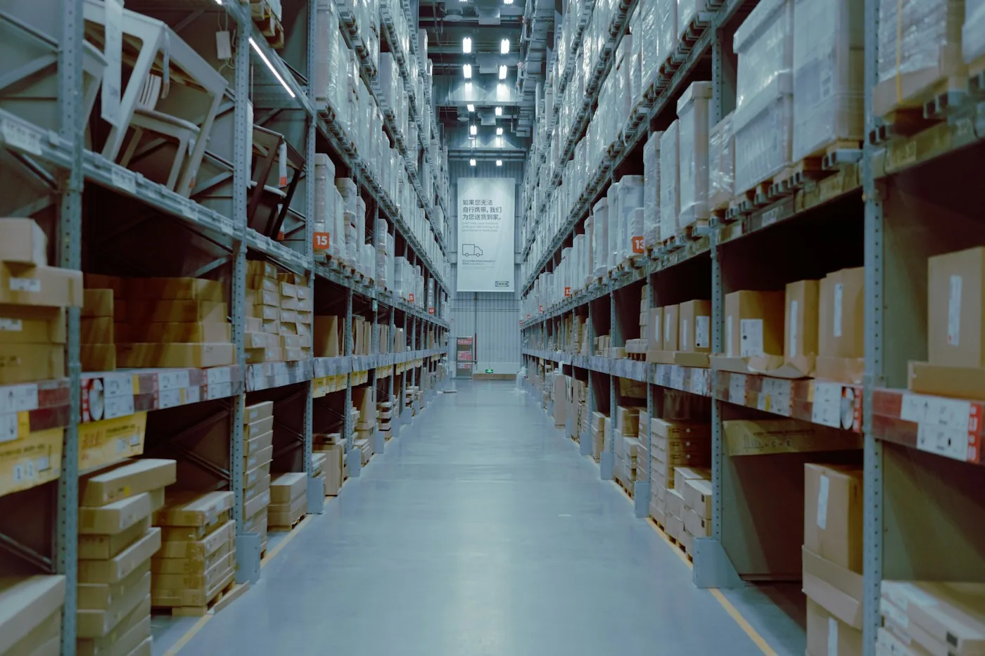 Long warehouse aisle between tall racks of boxed inventory.