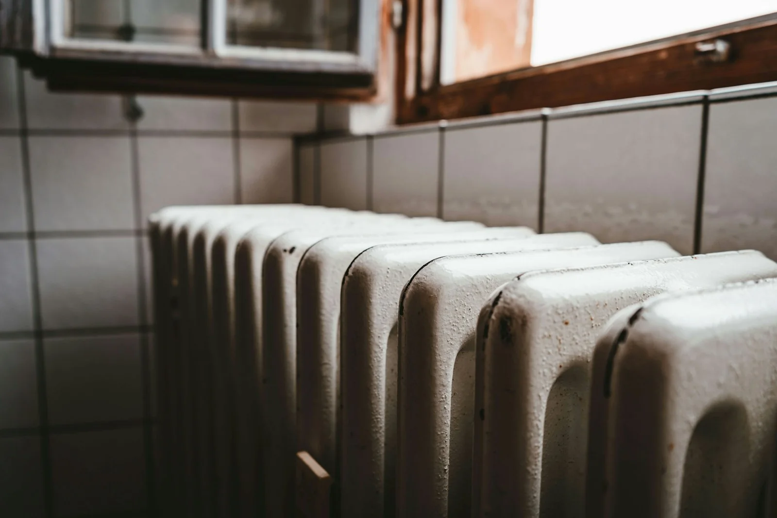 Cast-iron radiator beneath an open wooden-framed window.