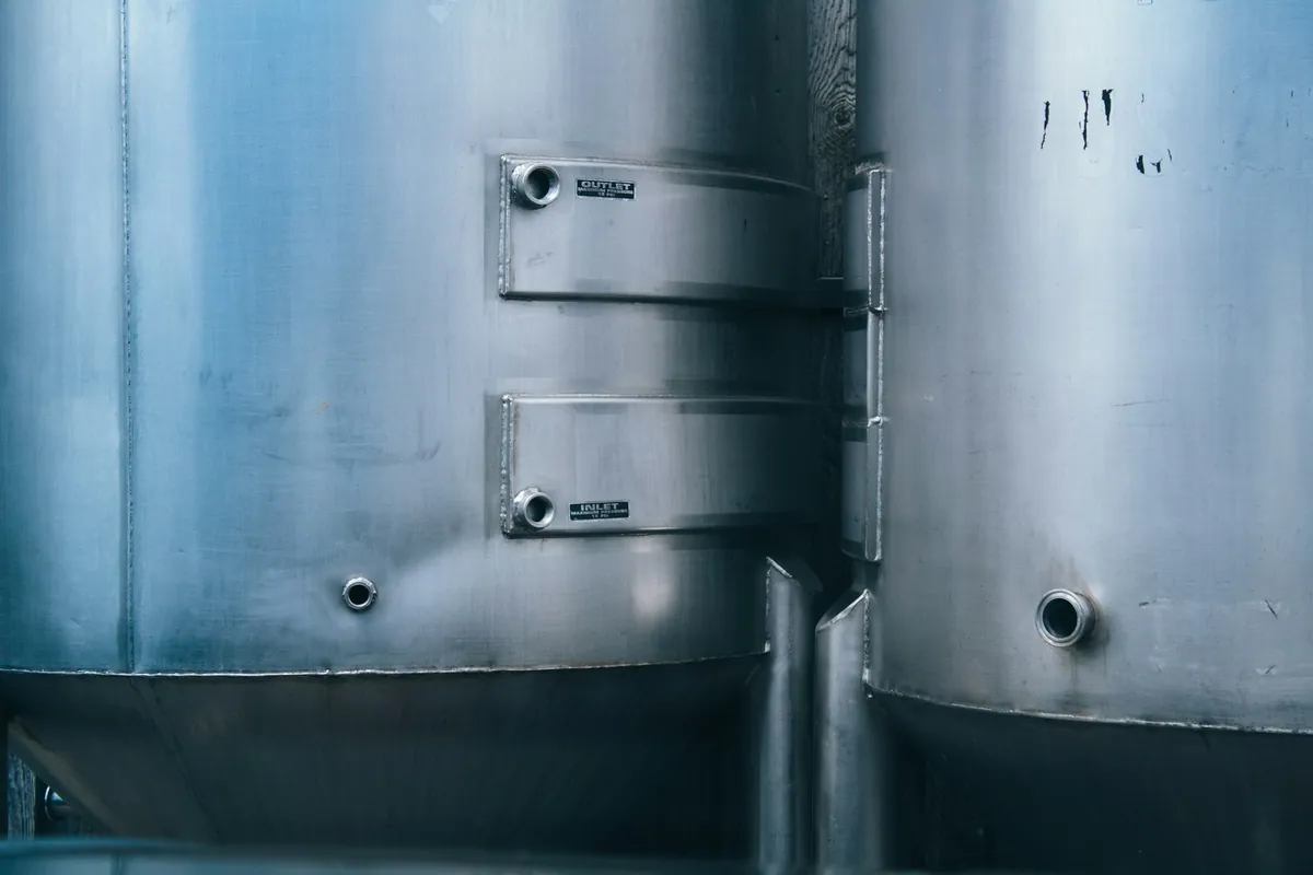 Close view of cylindrical stainless-steel tank walls and access fittings.