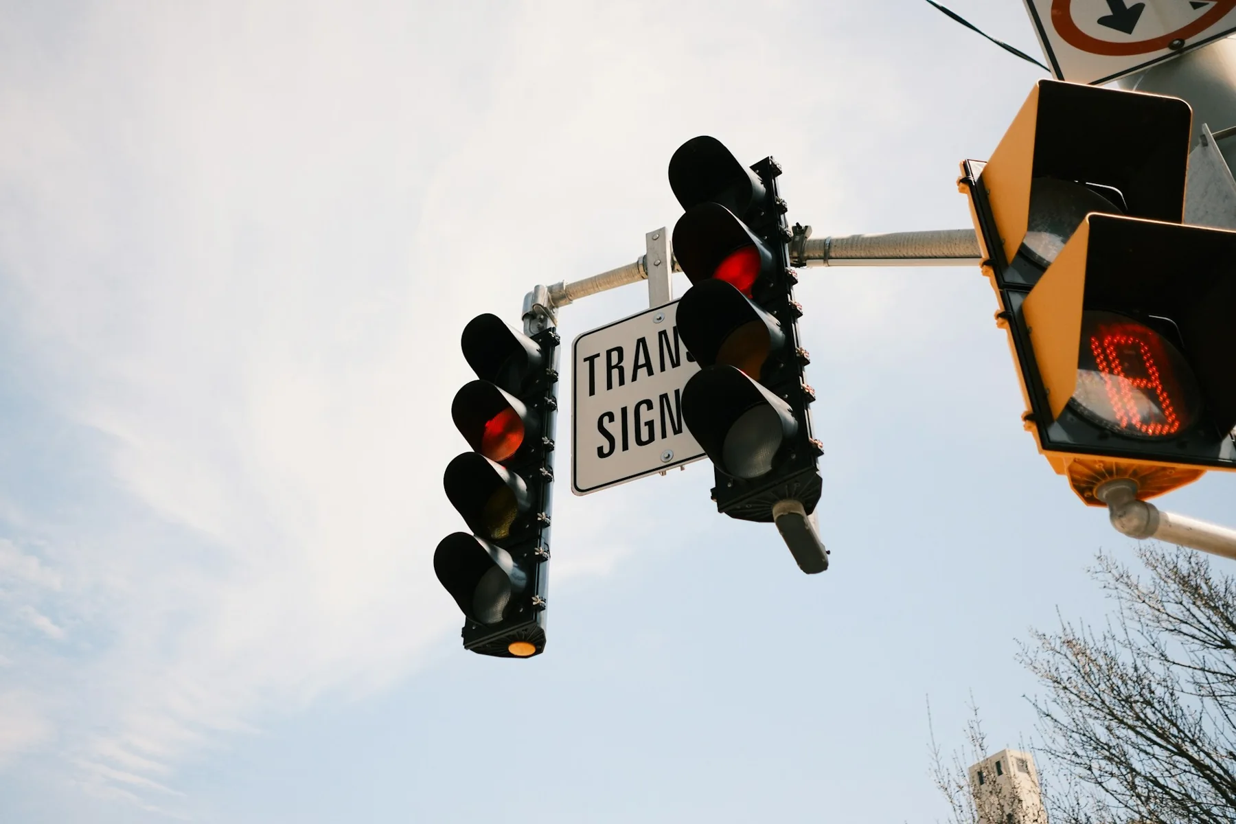 Two overhead traffic-signal heads showing red above a street intersection.