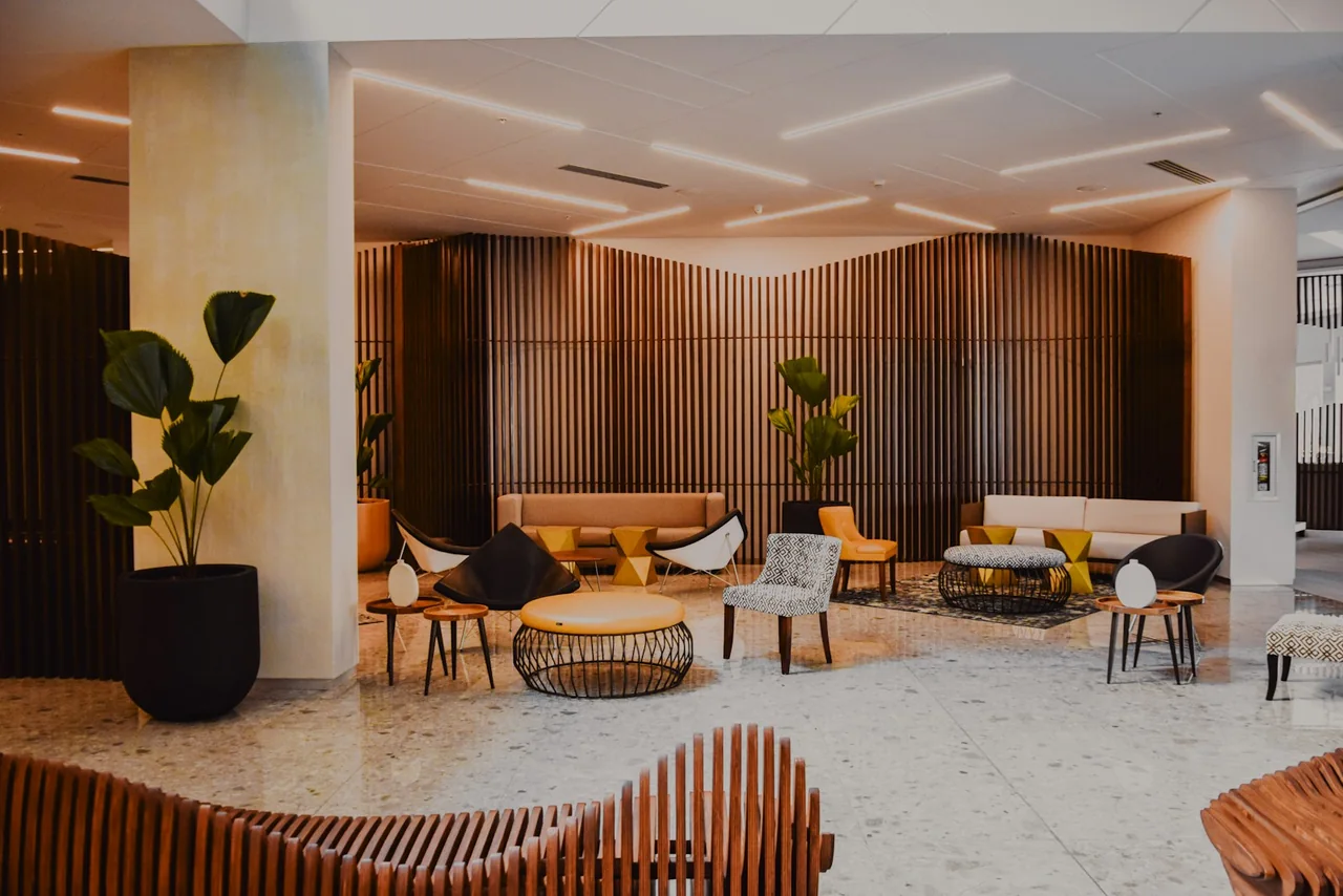 Hotel lobby seating beneath a ceiling with recessed lighting and ventilation openings.