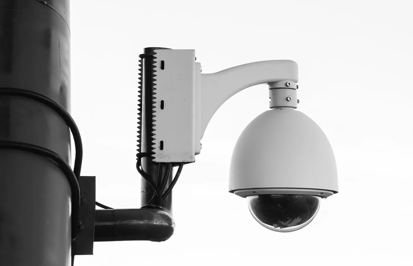 Dome surveillance camera and its mounting bracket on a pole.