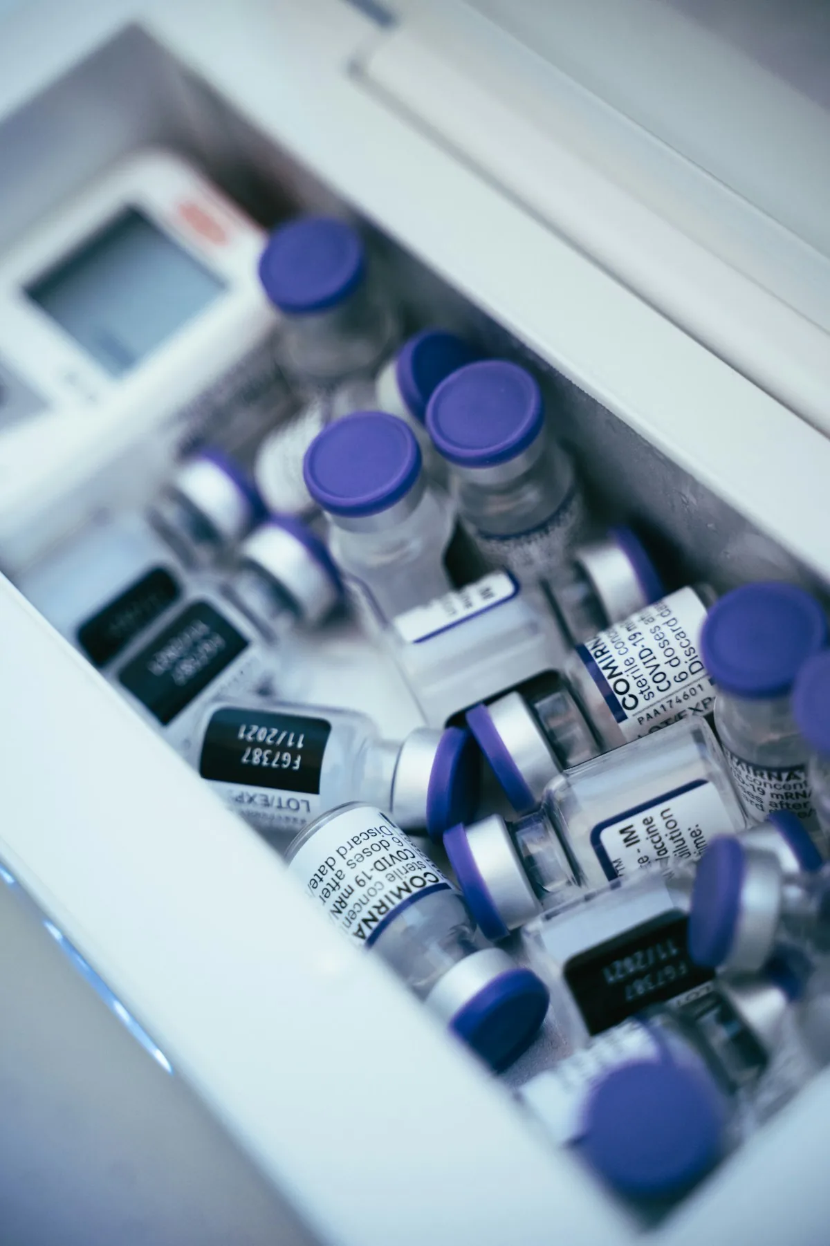 Capped vials arranged in compartments inside a white storage tray.