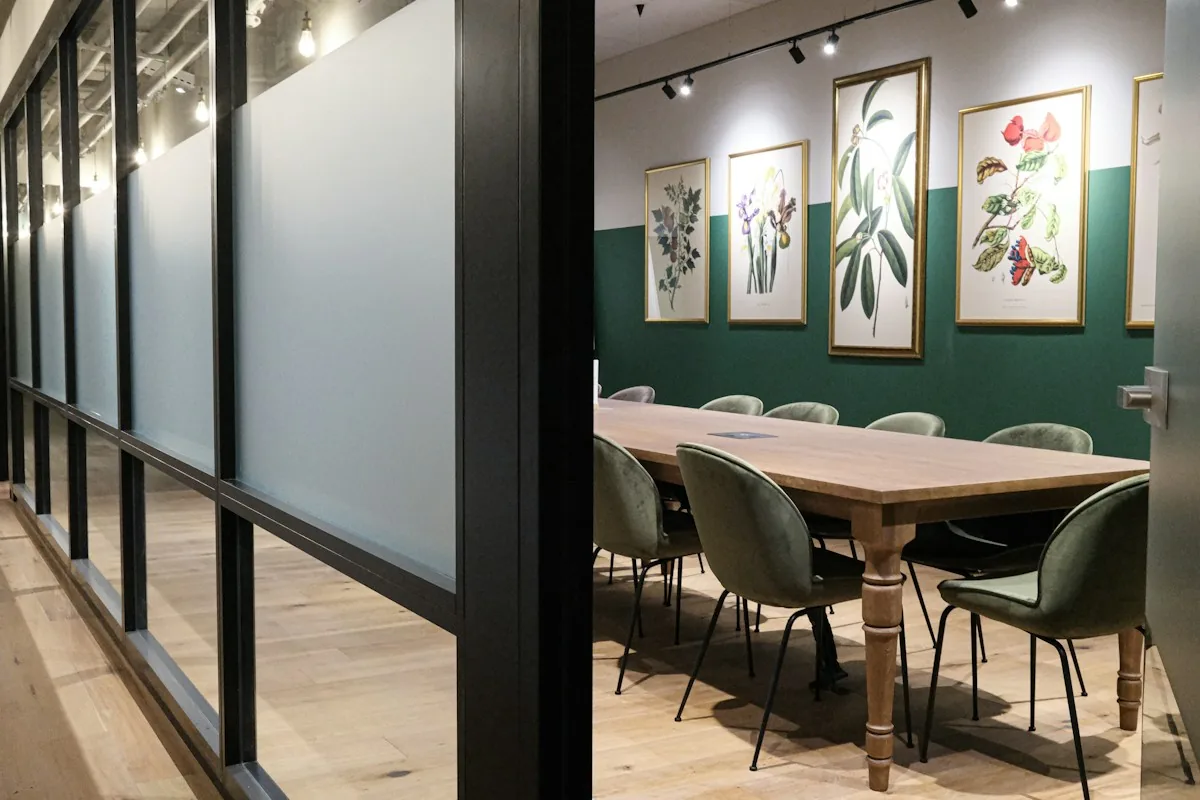 A glass-walled meeting room viewed from an office corridor.