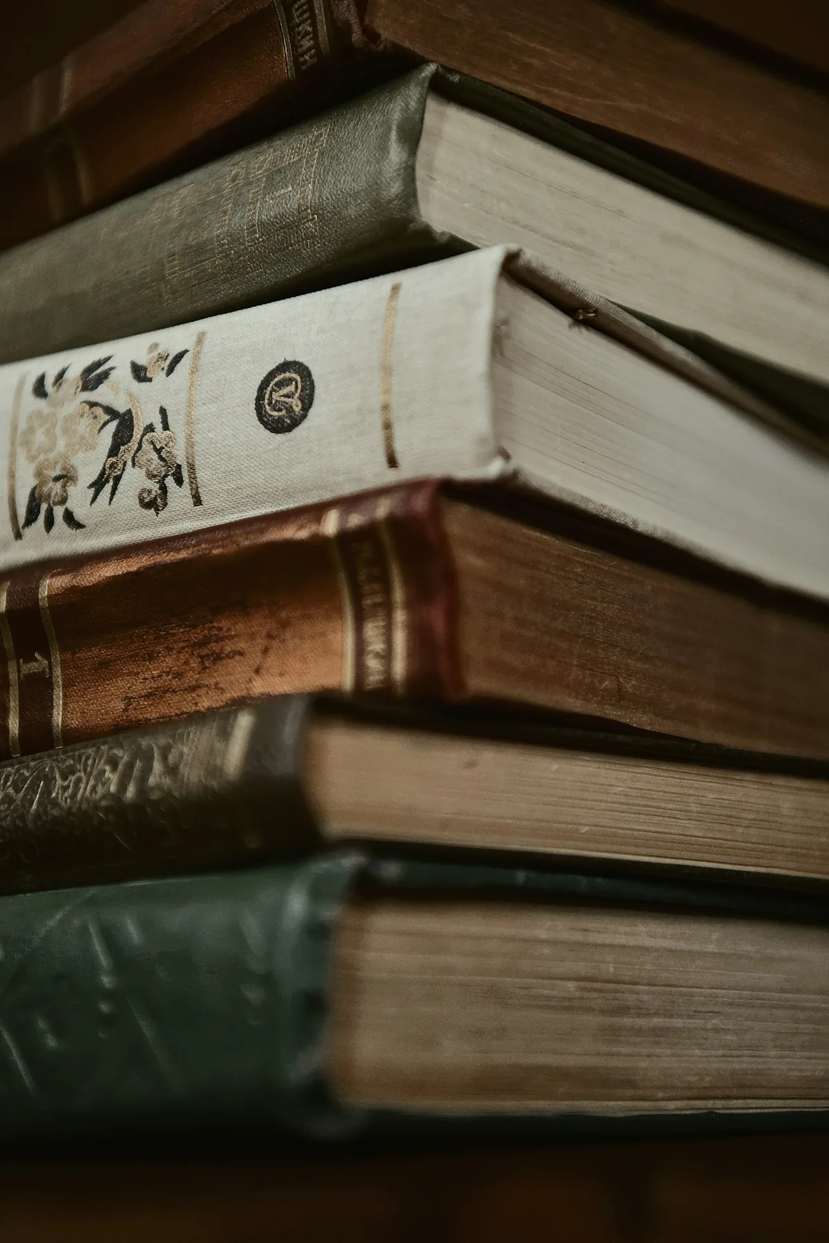 Close-up of worn book bindings and page edges in a stack of old books.