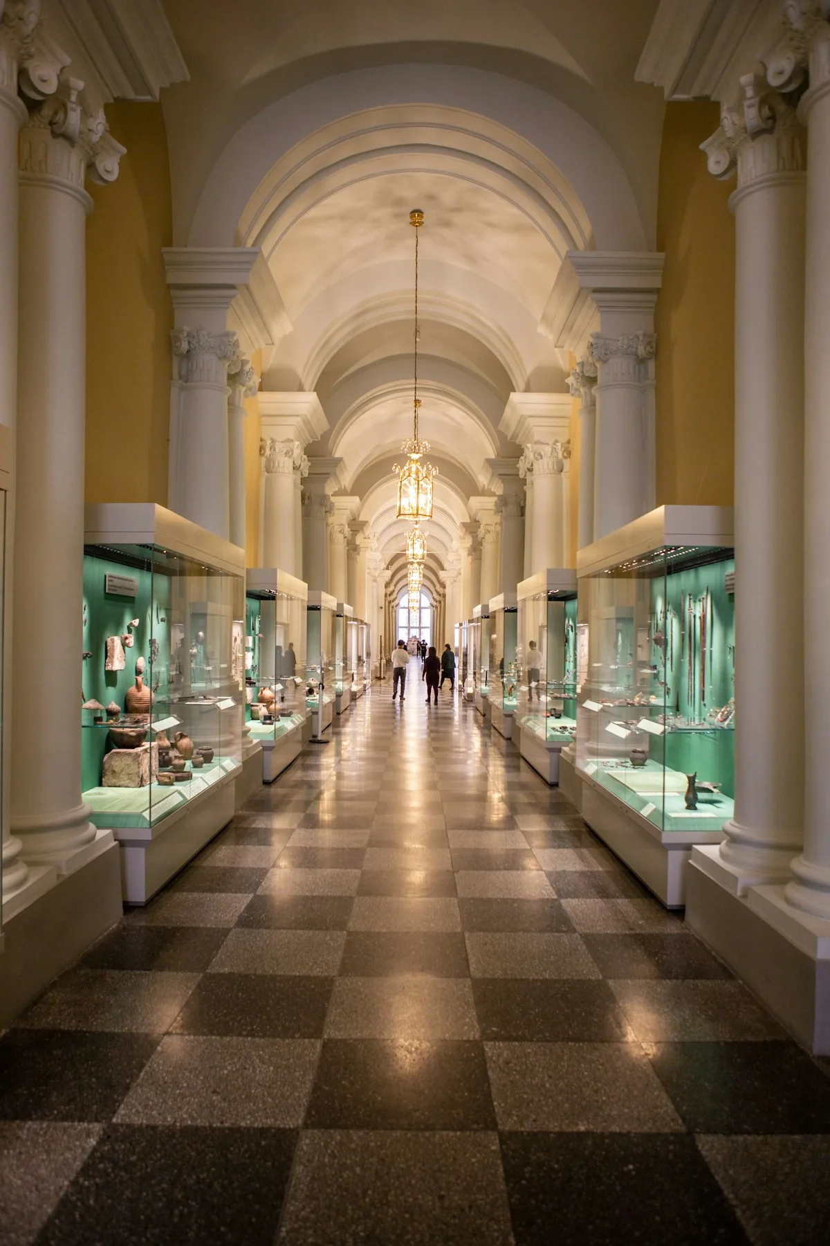 Glass cases of historic artifacts line a museum corridor beneath arched ceilings.